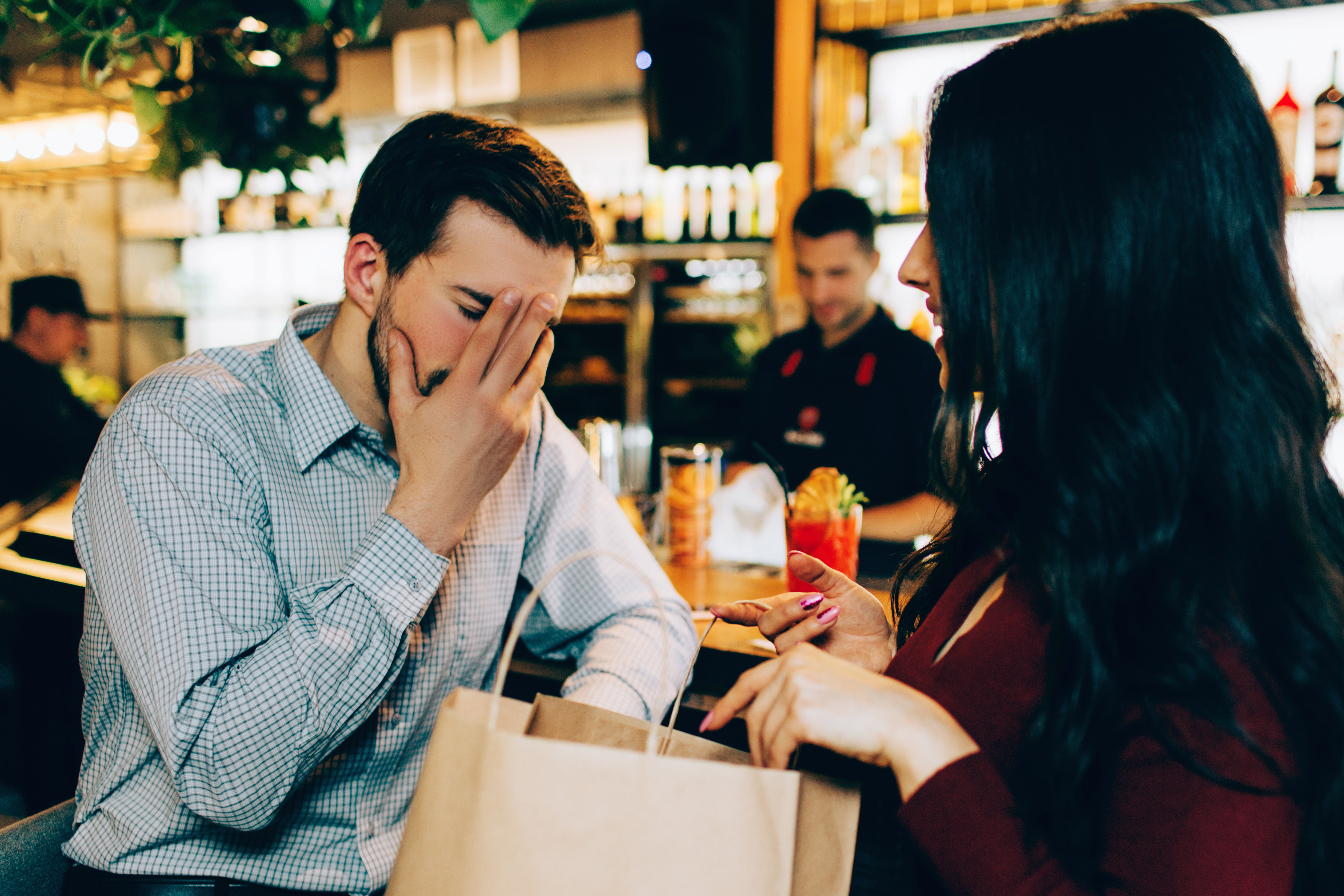 Un hombre apoya la cara en la mano mientras la mujer que tiene delante sigue hablando. | Foto: Shutterstock