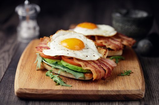 Tocino casero, huevo frito con aguacate, tomate y hojas de rúcula en pan de soda frito | Foto: Getty Images