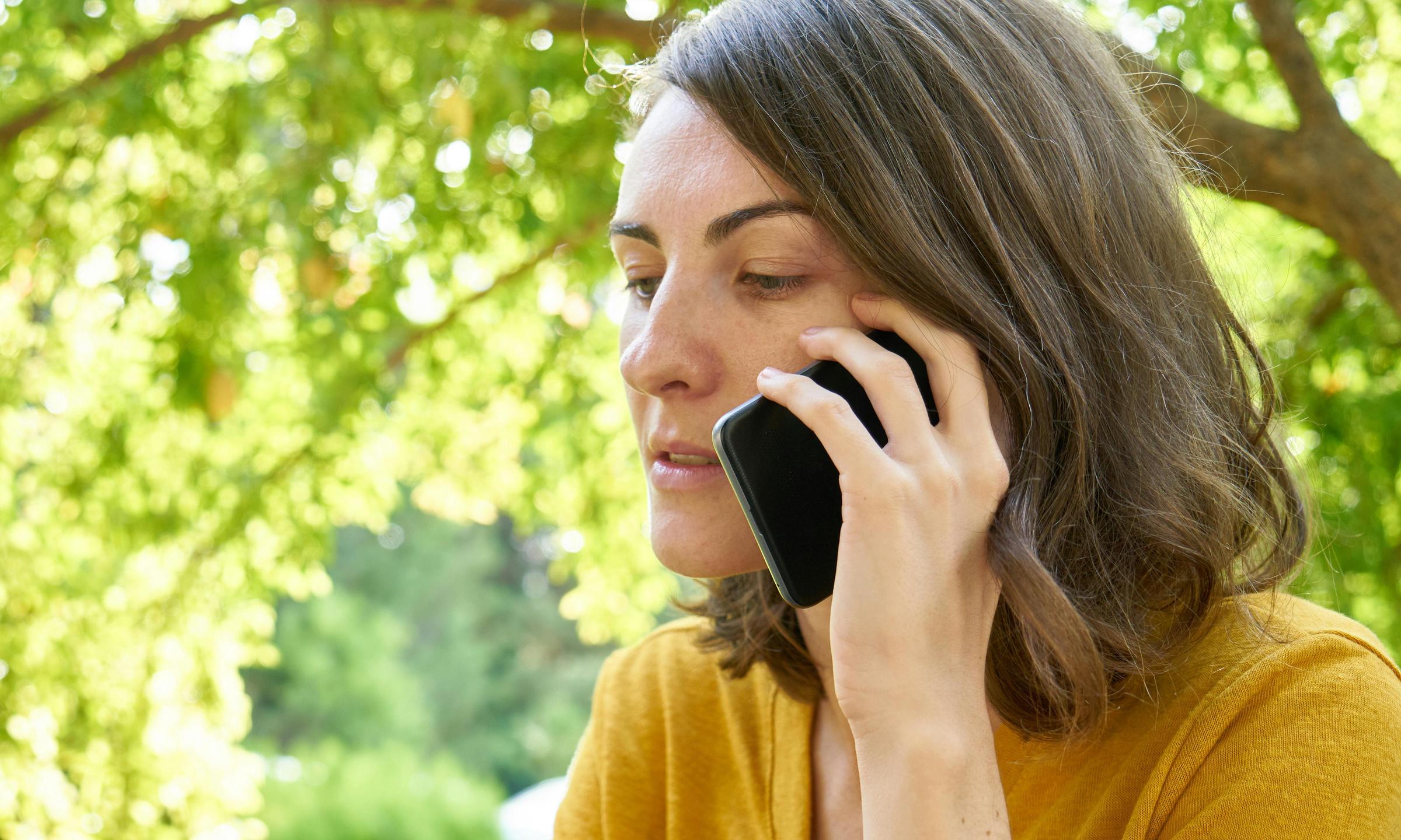 Una mujer haciendo una llamada por teléfono móvil al aire libre | Fuente: Pexels