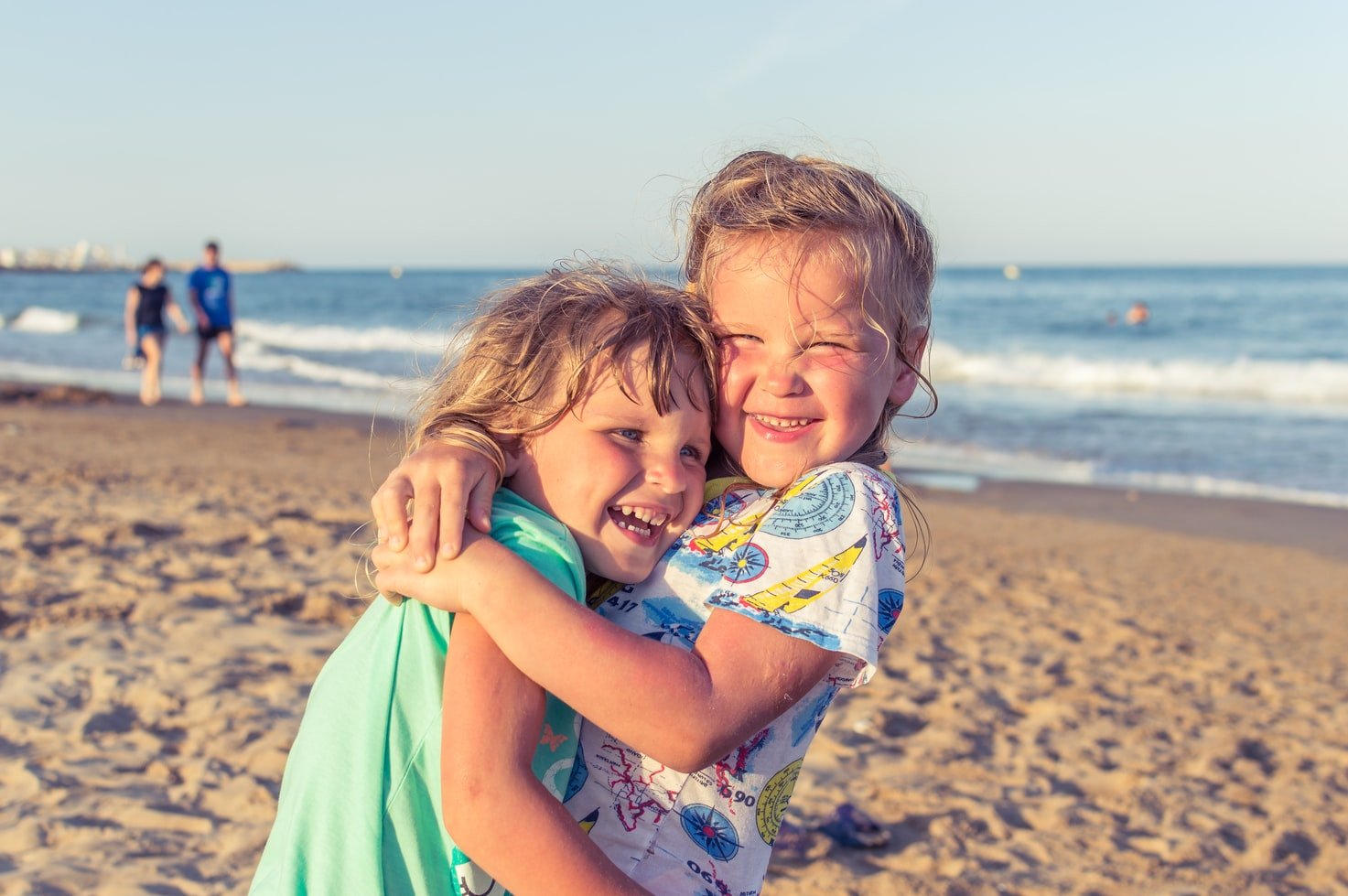 Dos niñas se abrazan con cariño mientras disfrutan de un día de playa. | Foto: Unsplash