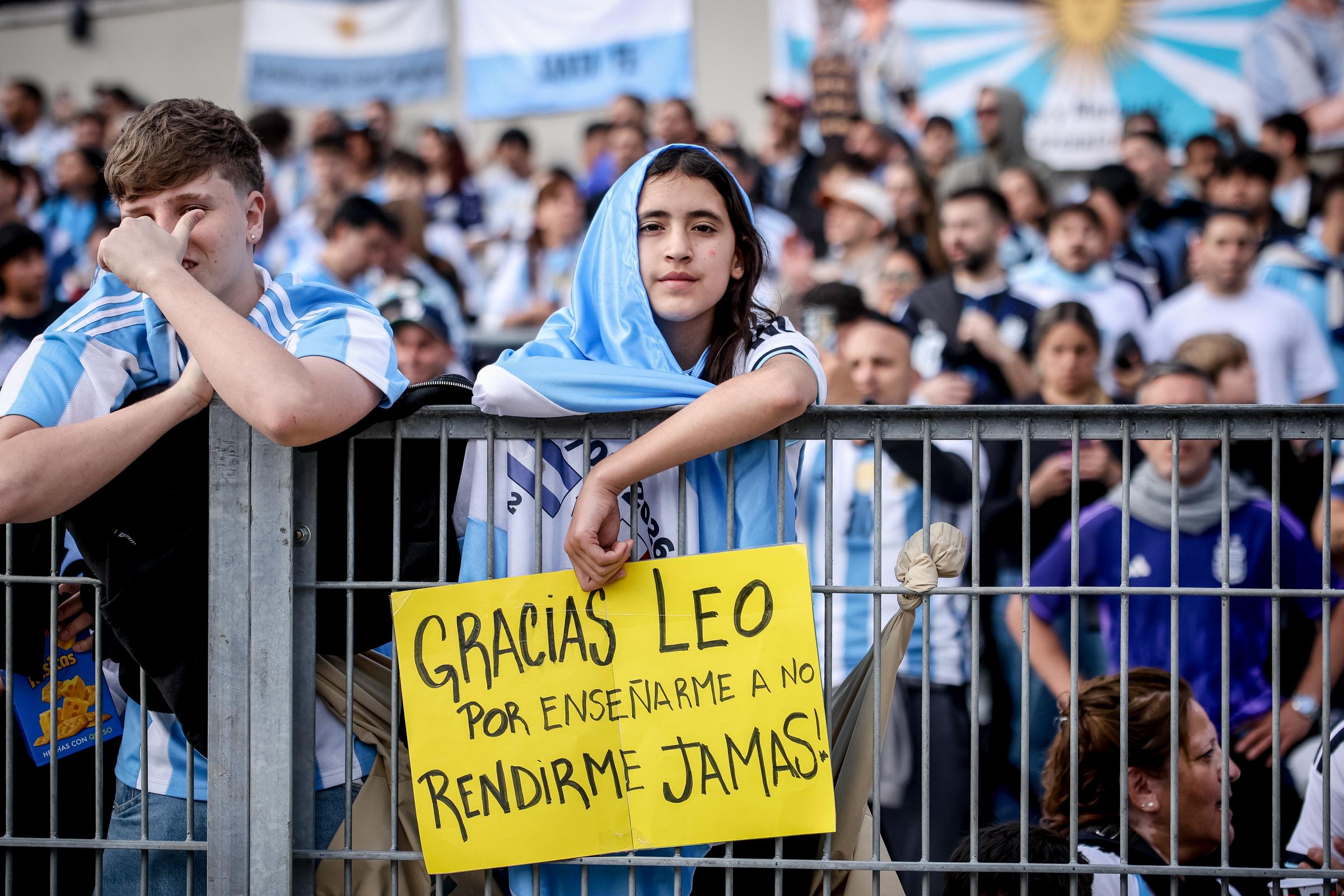 Una joven aficionada de la Selección Argentina se apoyó sobre la barandilla de la tribuna exhibiendo un cartel amarillo con la frase manuscrita: "GRACIAS LEO POR ENSEÑARME A NO RENDIRME JAMAS!", en la previa del partido amistoso contra Benín el 6 de octubre de 2026 en Buenos Aires, Argentina. La emotiva muestra de agradecimiento formó parte de la despedida a Lionel Messi en su último partido con el combinado nacional, rodeada por una multitud vestida de celeste y blanco. | Fuente: Getty Images