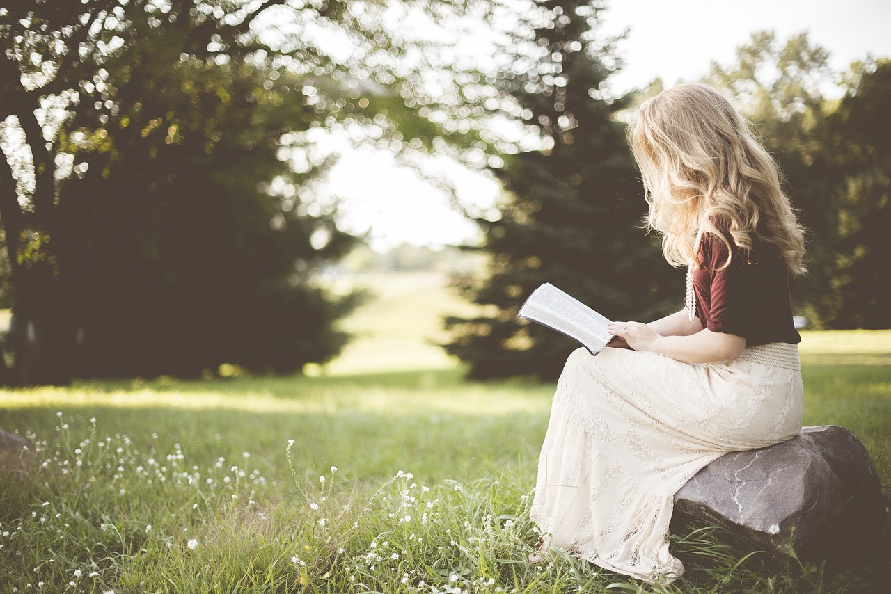 Una mujer leyendo un libro al aire libre | Foto: Pixabay