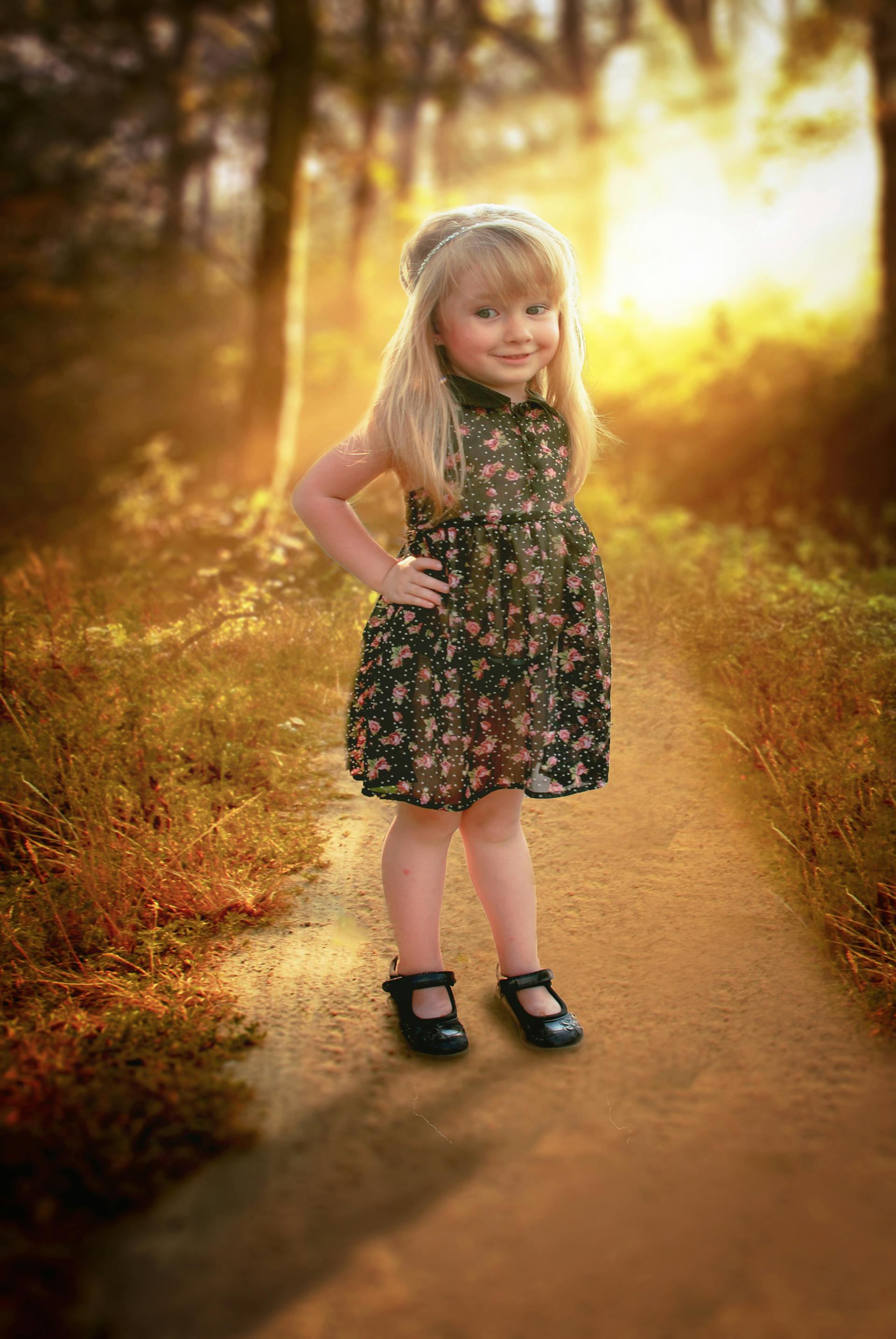 Una niña feliz con un vestido de flores de pie en un camino | Fuente: Pexels