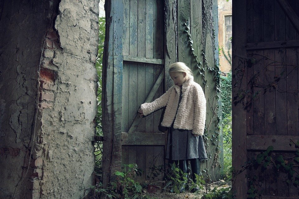 Niña cerca de una puerta de madera. | Imagen: Pixabay
