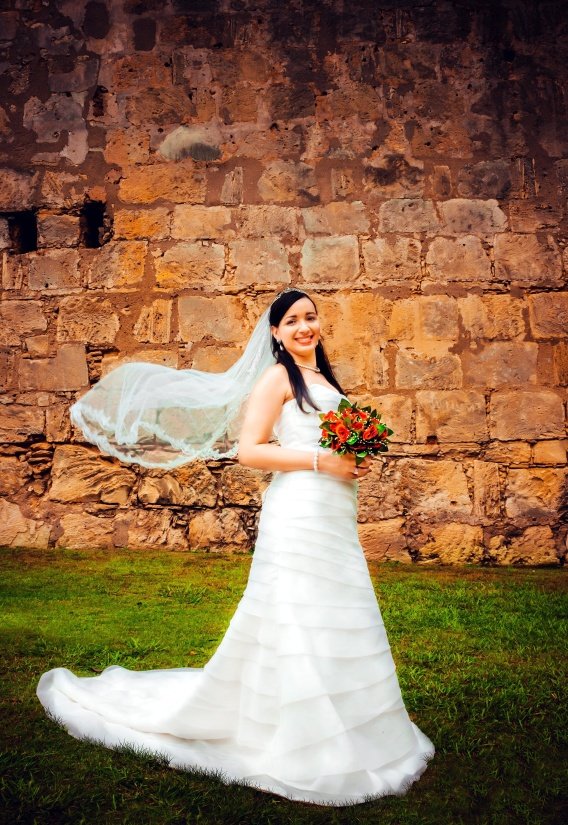 Mujer parada sobre el pasto con vestido de novia y velo, sosteniendo un ramo de flores. | Imagen: Pixnio