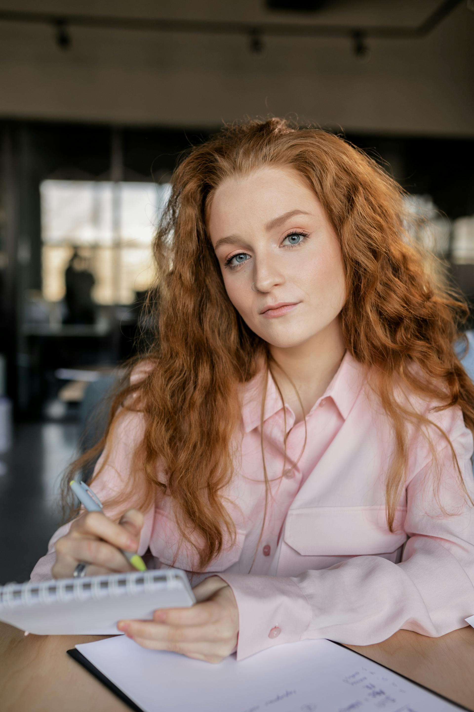 Una mujer con un bolígrafo y un cuaderno en la mano | Fuente: Pexels