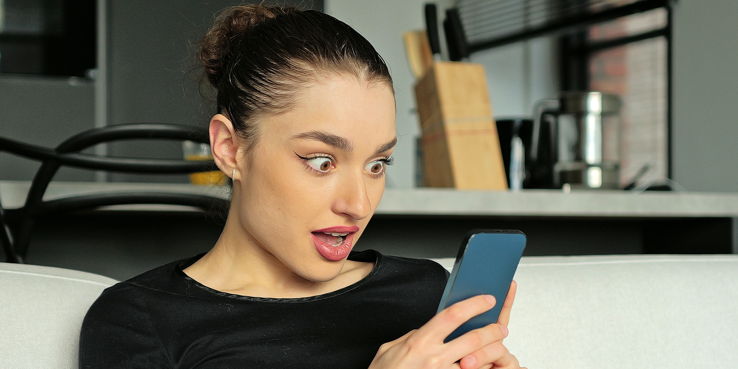 Mujer conmocionada mirando su teléfono | Fuente: Shutterstock