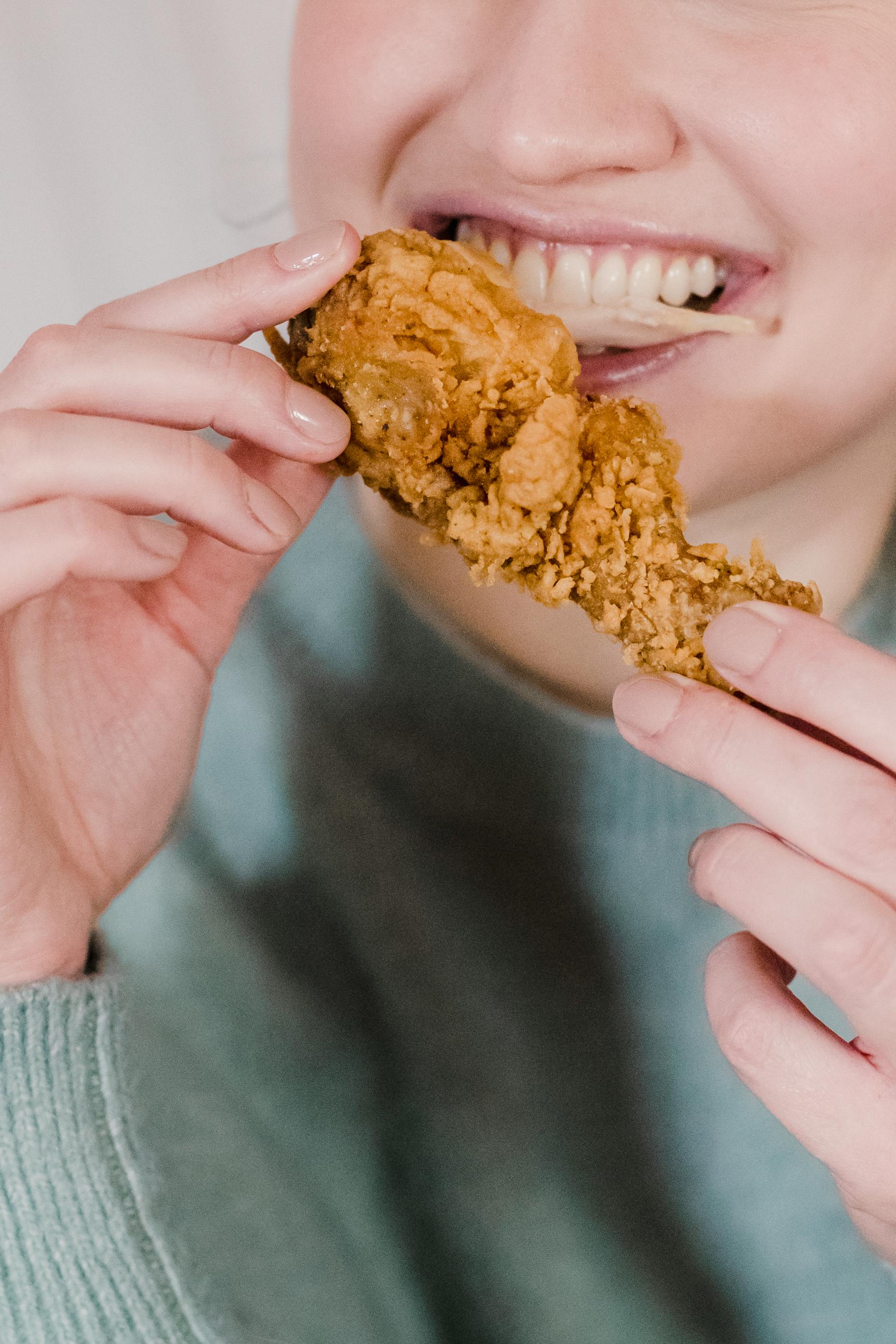 Una persona comiendo pollo frito | Fuente: Pexels