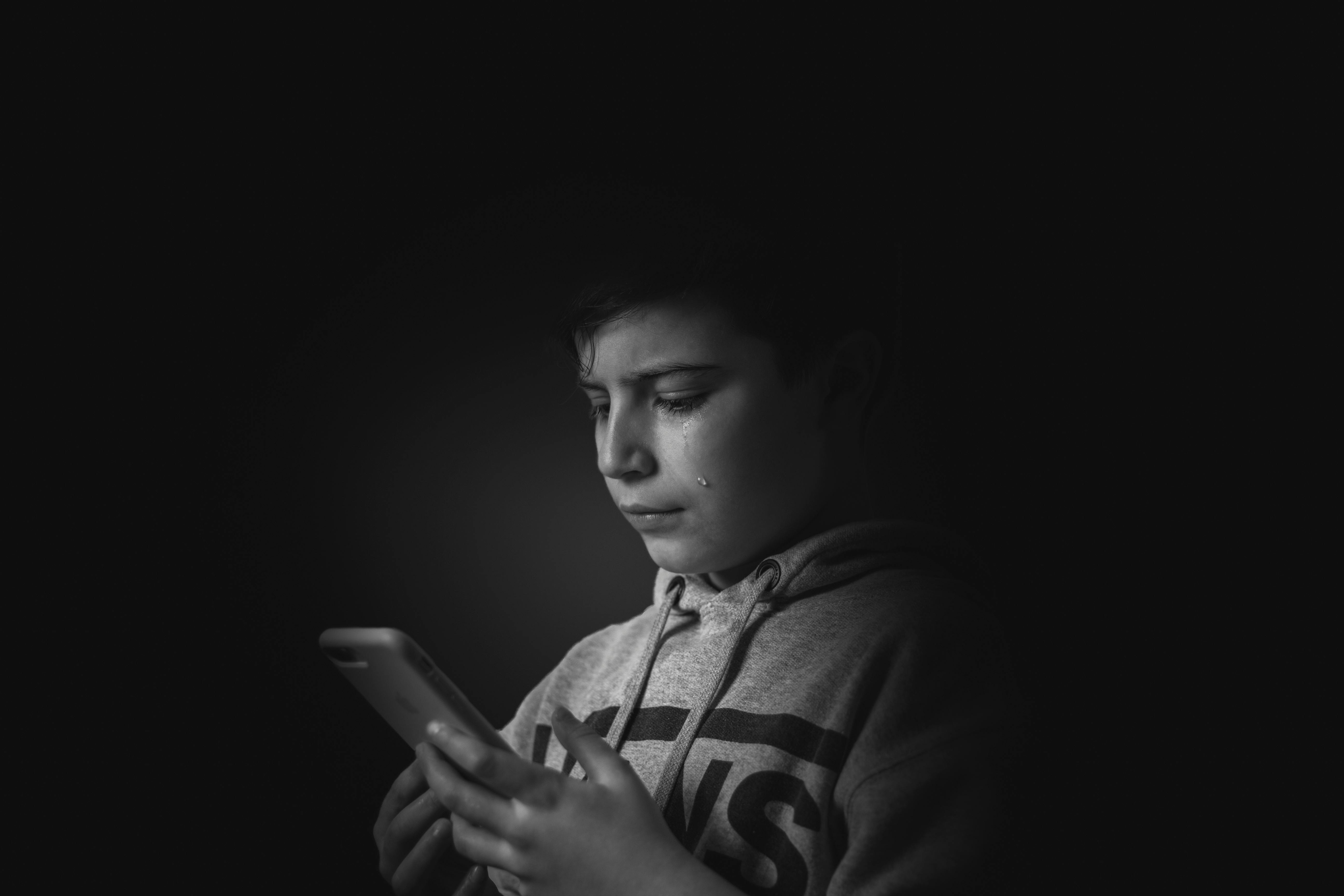 Un niño llorando mirando su teléfono | Fuente: Pexels