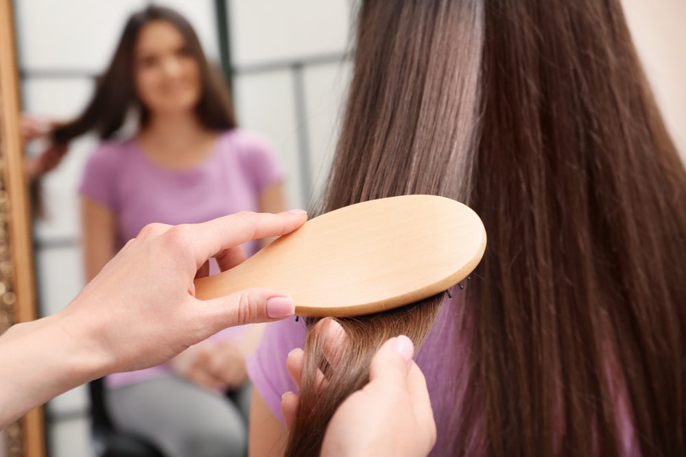 Mujer cepillando el cabello de su amiga. | Foto: Shutterstock