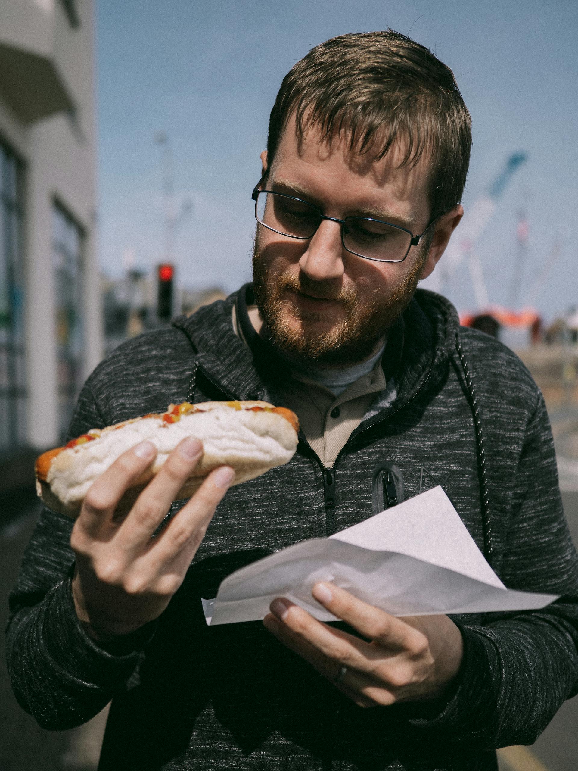 Un hombre a punto de comerse un perrito caliente | Fuente: Pexels