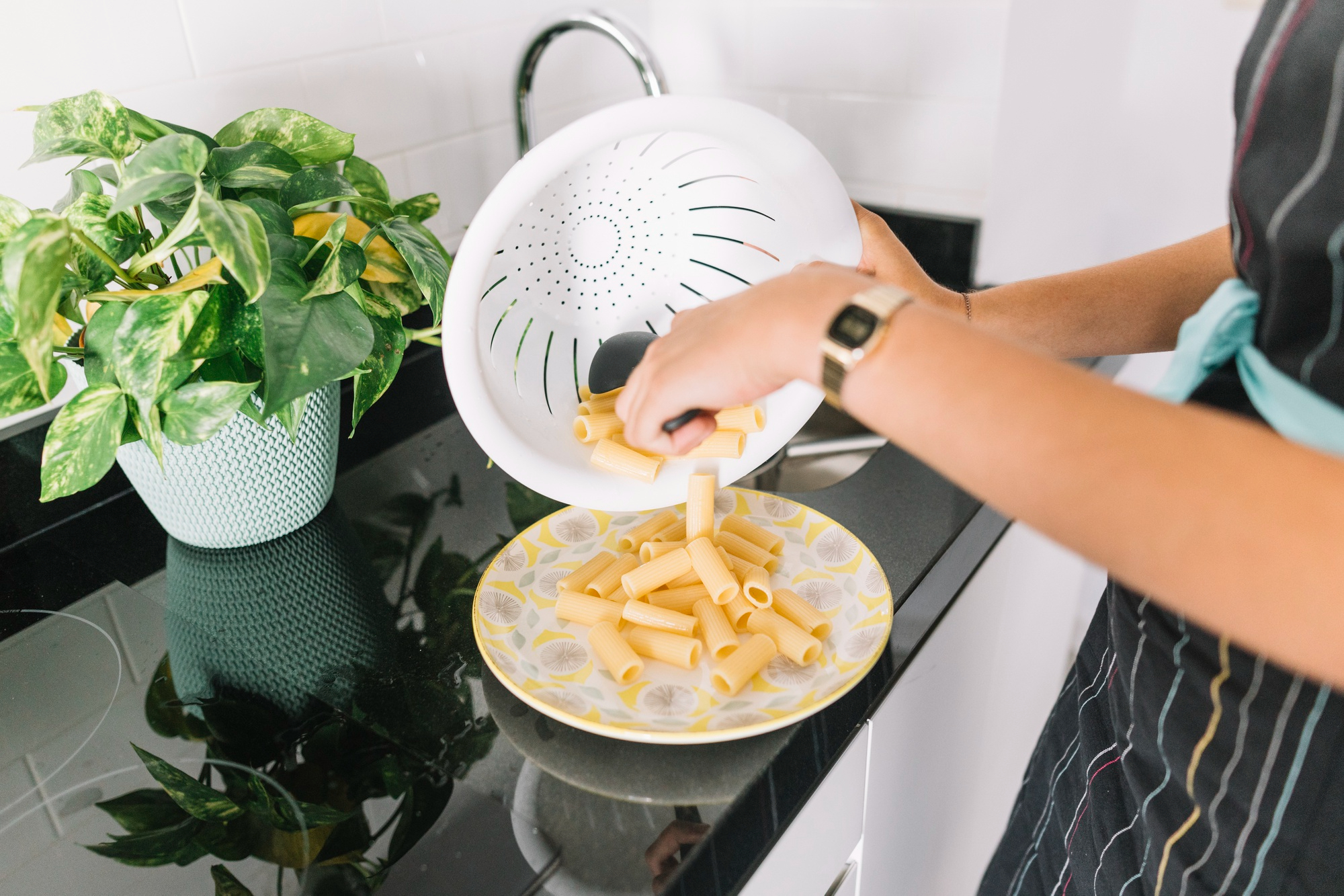 Una mujer vierte pasta cocida en un plato | Fuente: Freepik