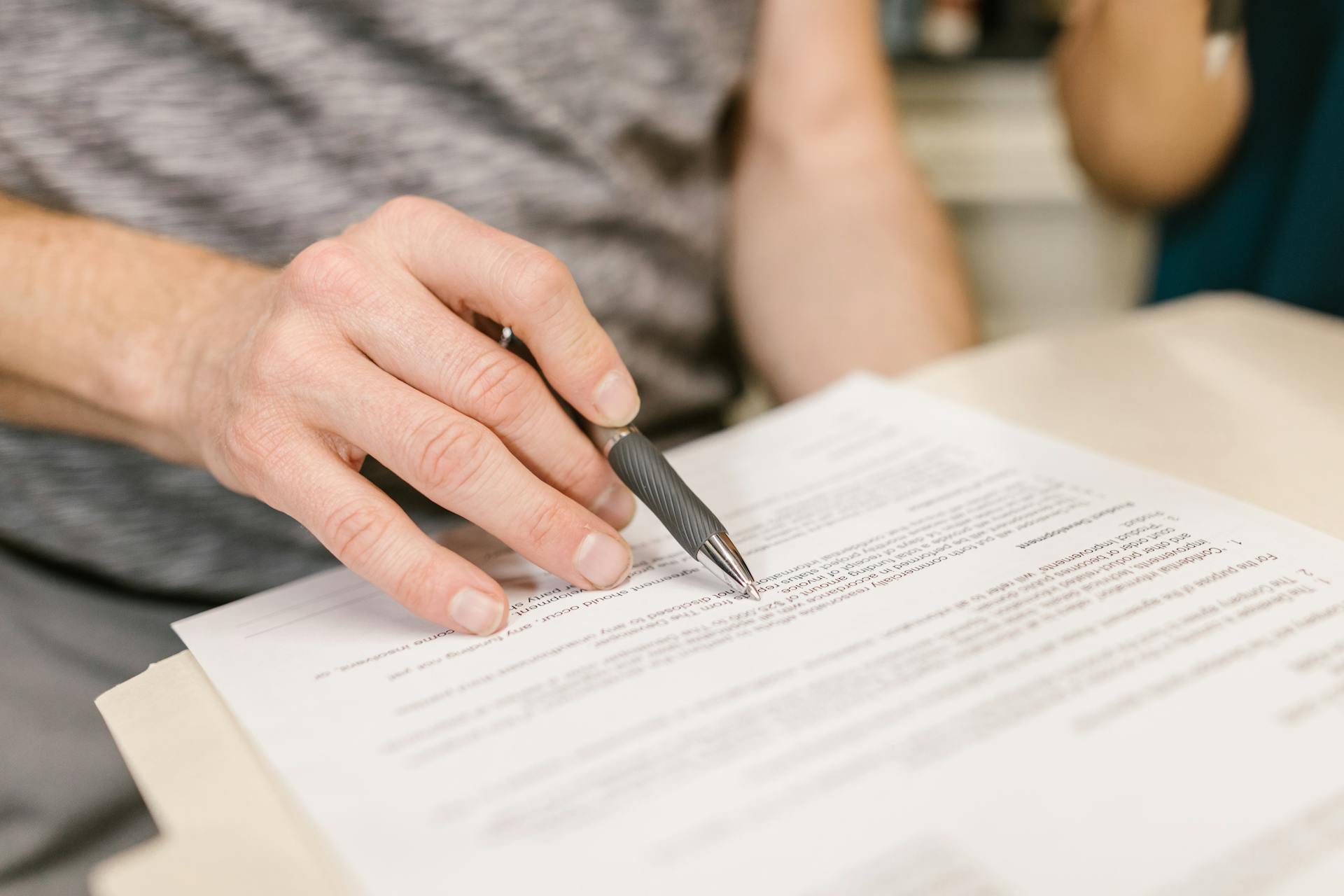 Persona sosteniendo un bolígrafo sobre documentos legales | Foto: Pexels