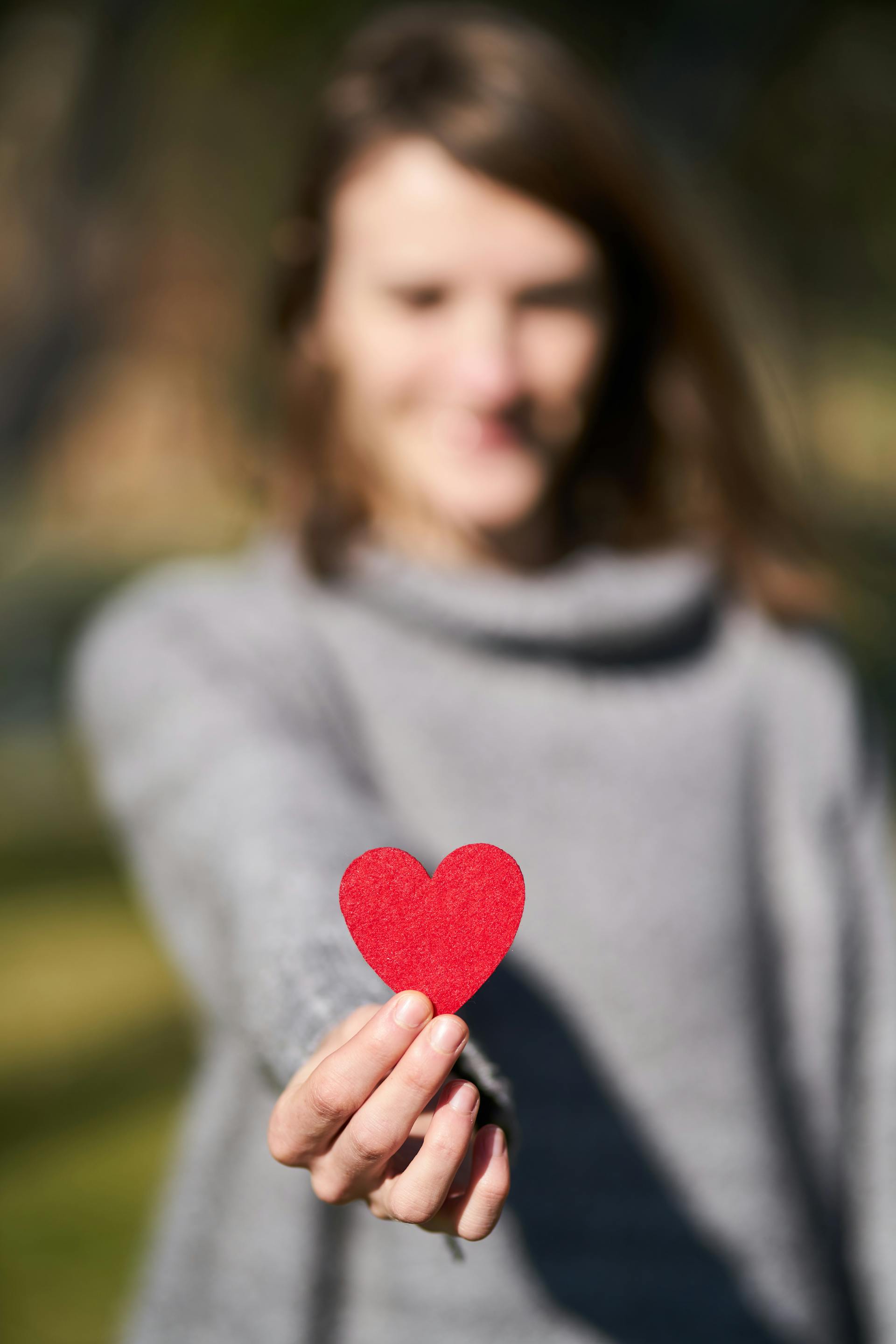 Una mujer sujetando un recorte en forma de corazón | Fuente: Pexels