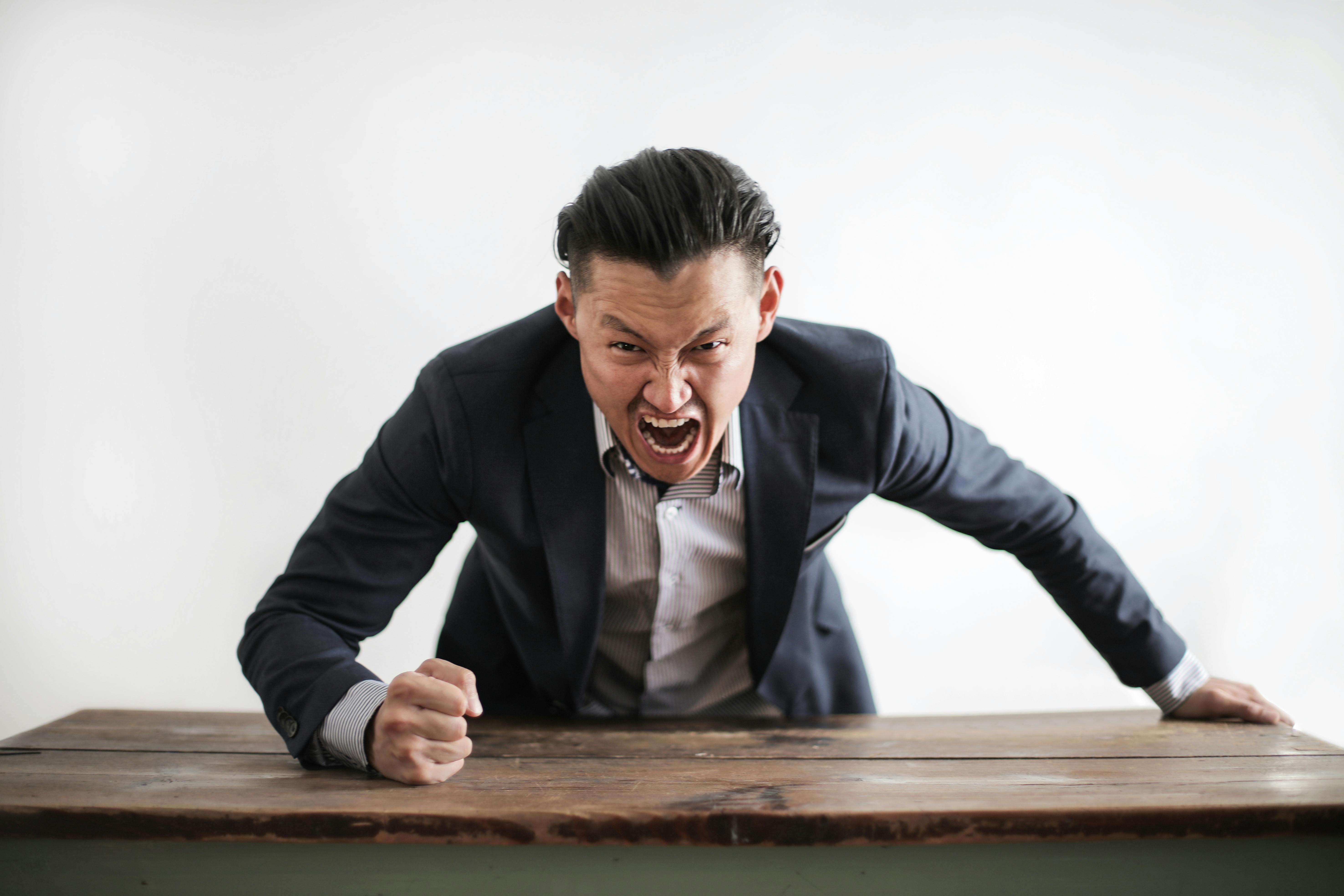 Un hombre enfadado gritando sobre una mesa | Fuente: Pexels