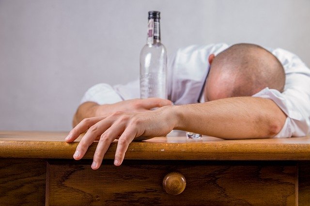 Un hombre recuesta su cabeza con una botella cerca. |  Foto: Pixabay