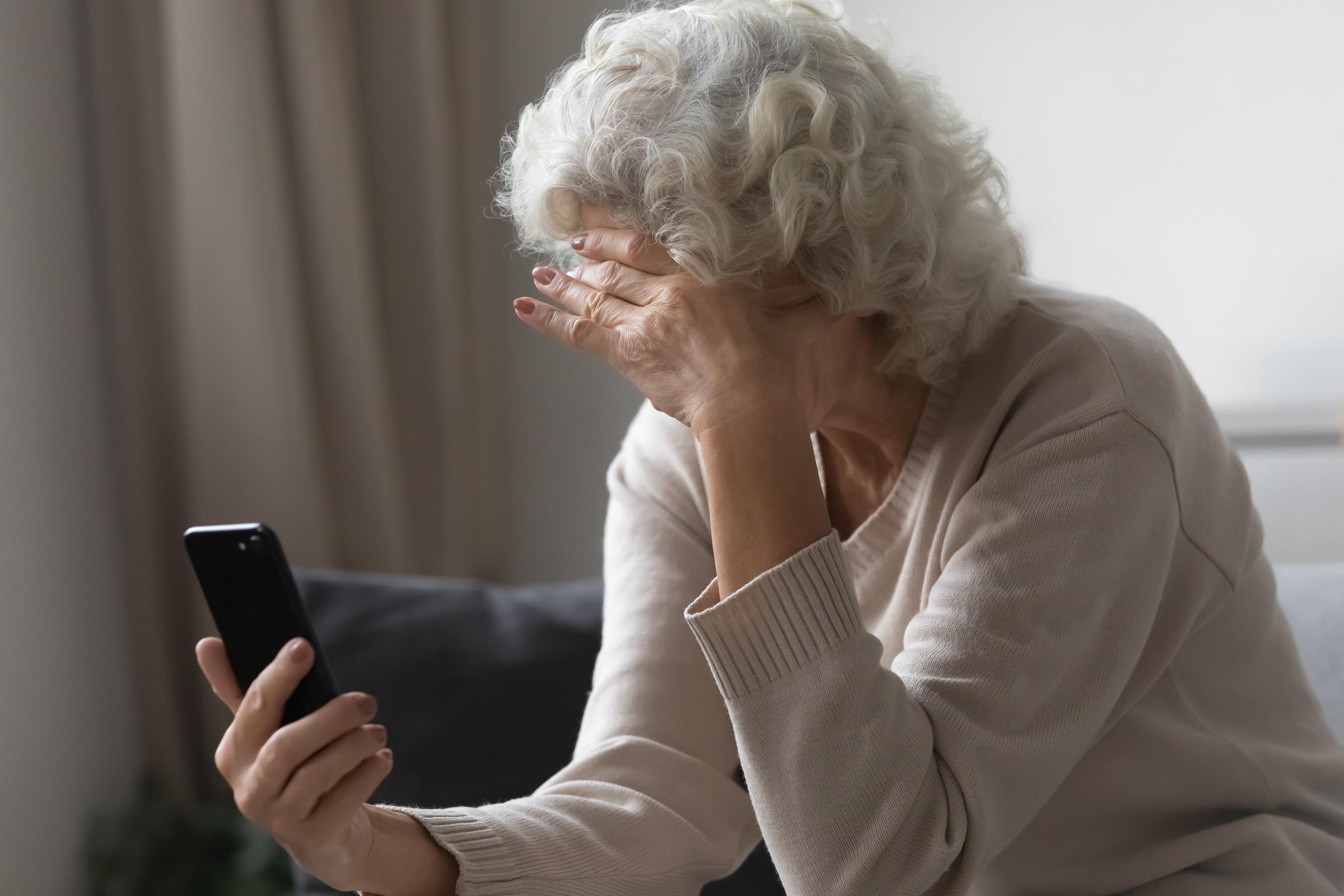Mujer mayor estresada mirando su teléfono | Fuente: Shutterstock