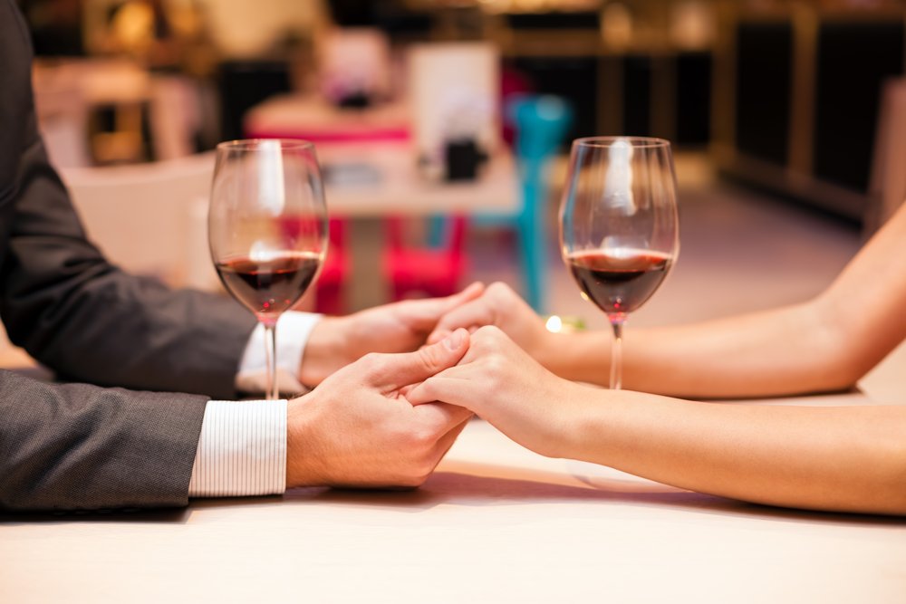 Hombre sostiene manos de mujer en un restaurante. | Foto: Shutterstock