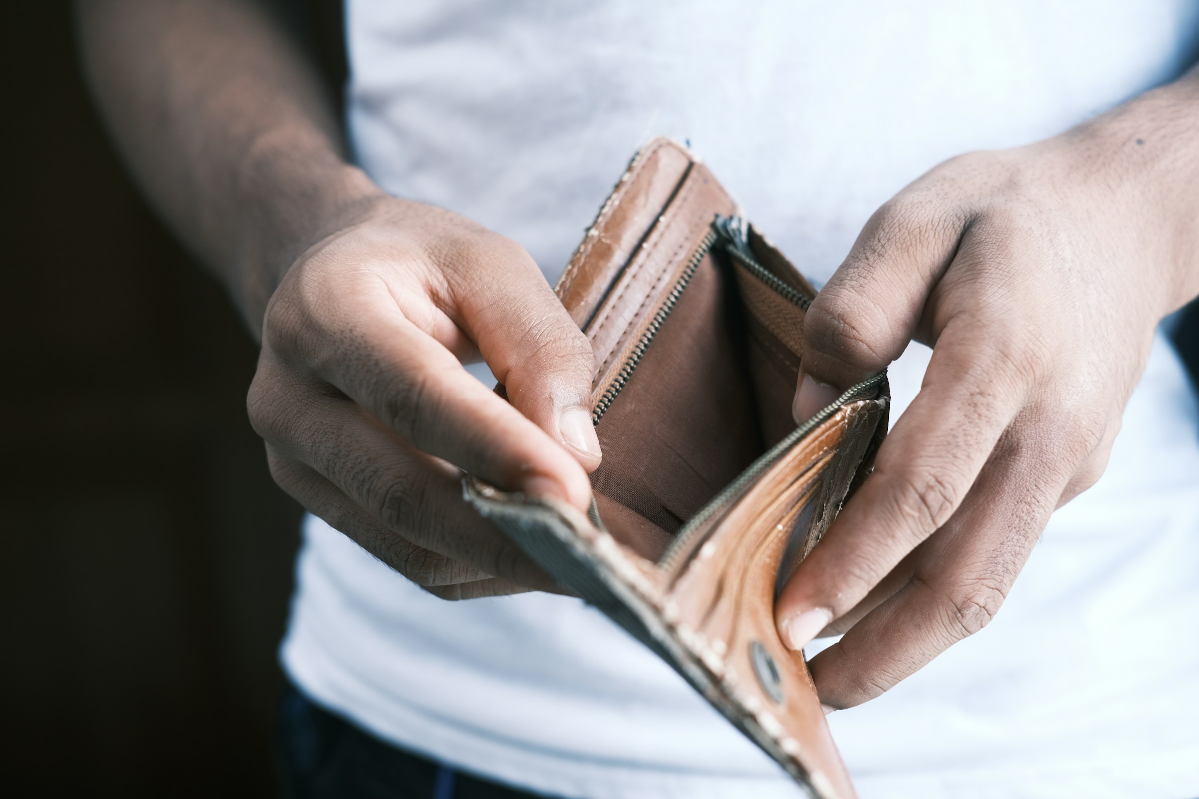 Un hombre abriendo una cartera vacía | Fuente: Unsplash