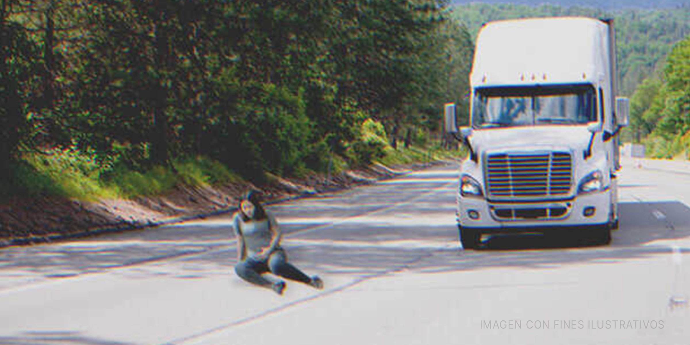 Mujer embarazada sentada en la via por donde pasa un camión | Foto: Shutterstock 