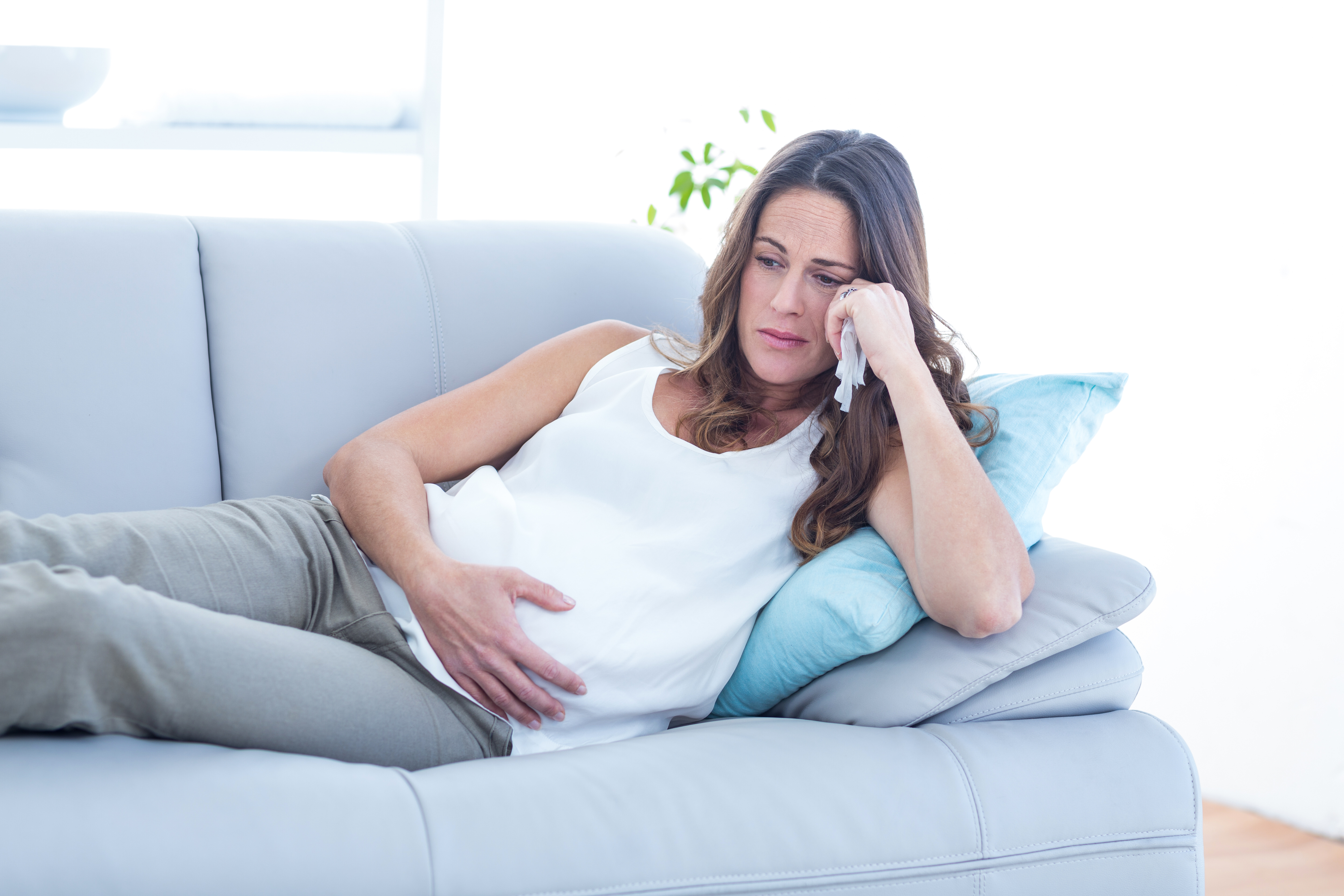 Una embarazada triste tumbada en el sofá | Foto: Shutterstock