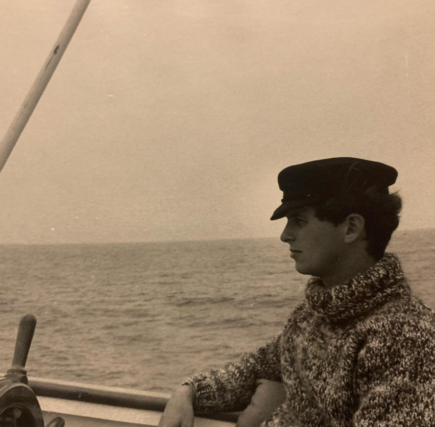 Una foto antigua muestra a Stephen Wyle, el padre de Noah Wyle, con una gorra de marinero y un suéter de punto grueso, sentado a bordo de un barco con el mar extendiéndose a sus espaldas. | Fuente: Instagram/therealnoahwyle