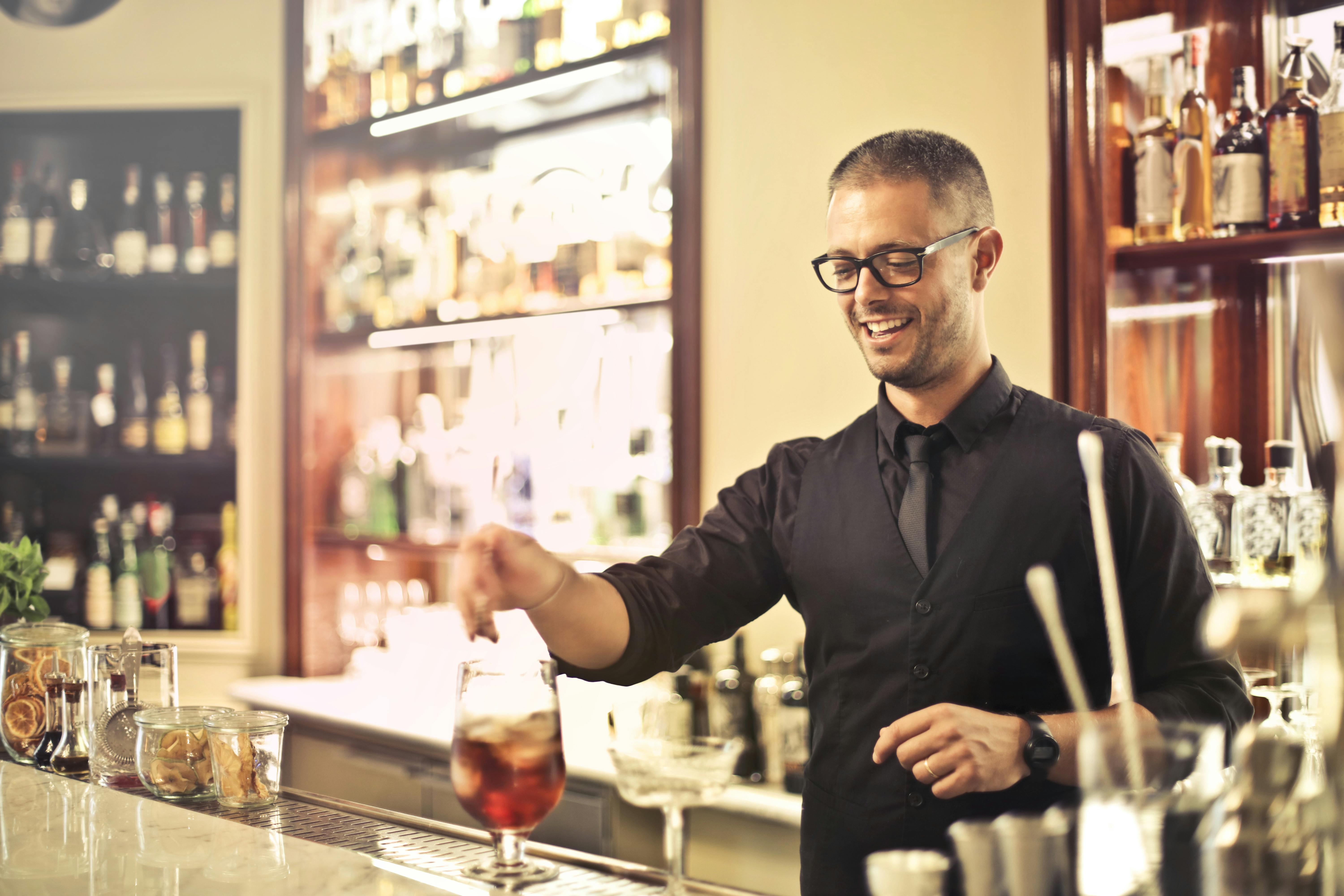 Un camarero sonriente preparando una bebida | Fuente: Pexels