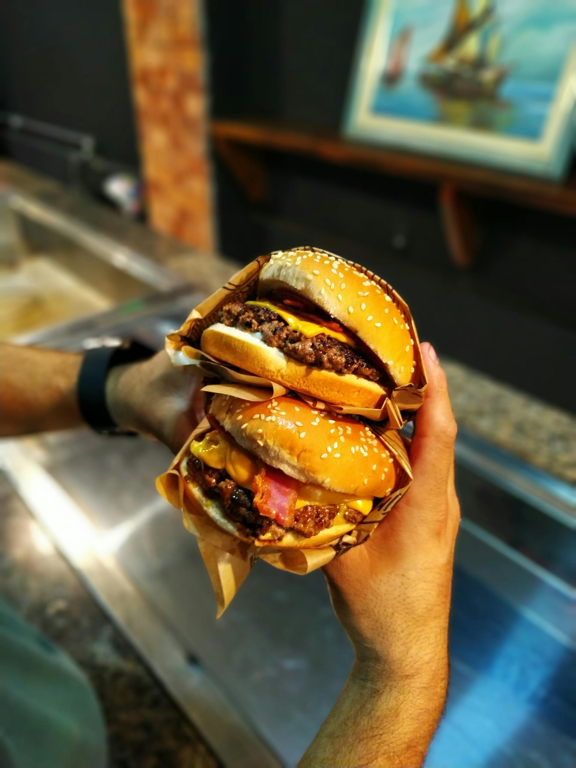 Primer plano de un hombre sujetando dos hamburguesas | Fuente: Pexels