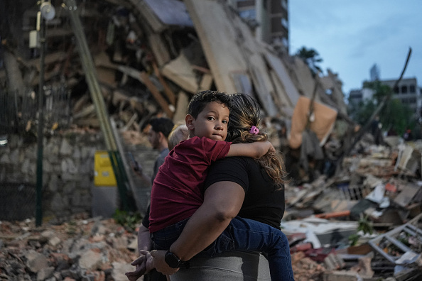 Personas caminan junto a un edificio colapsado tras el terremoto ocurrido en Caracas, Venezuela, el 25 de junio de 2026.
