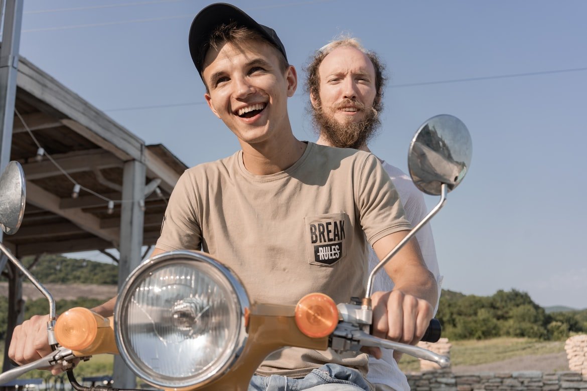 Dos jóvenes sonrientes en una motocicleta. | Foto: Unsplash