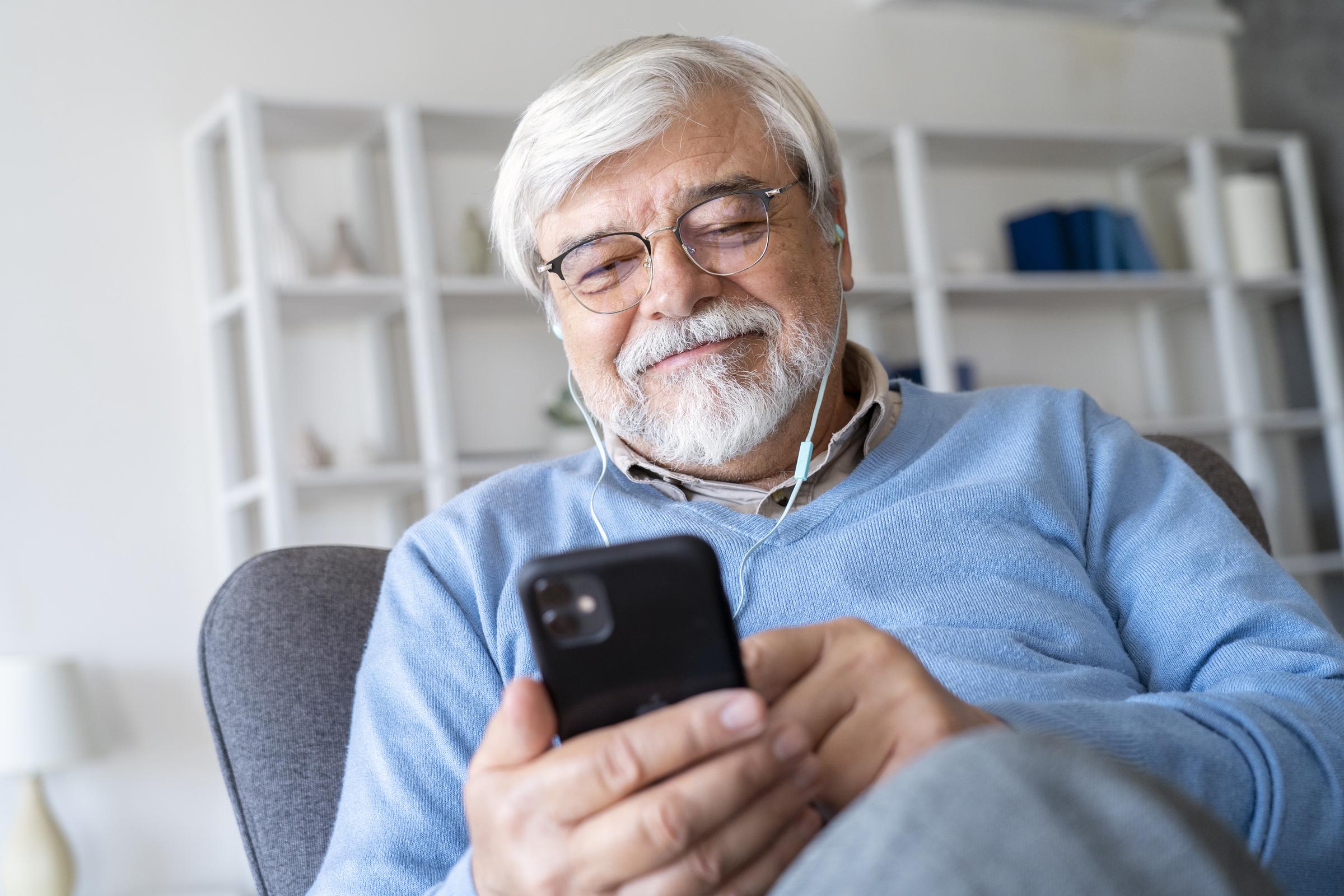 Hombre maduro mirando su teléfono y sonriendo | Fuente: Freepik