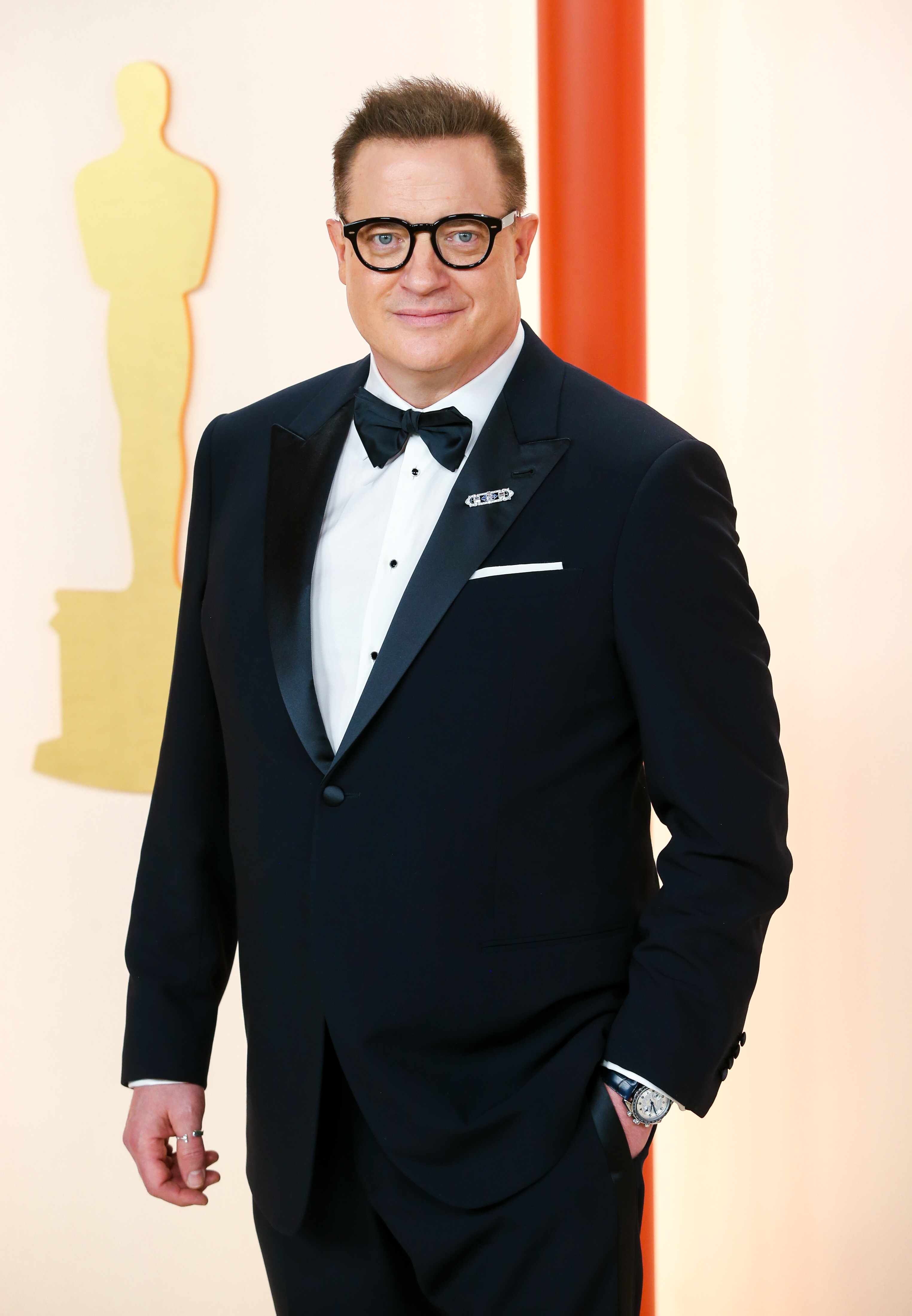 Brendan Fraser en los Óscar de 2023, donde lució un esmoquin de Giorgio Armani hecho a medida y un reloj vintage de Cartier, y completó su look en la alfombra roja con sus características gafas de montura negra. | Fuente: Getty Images