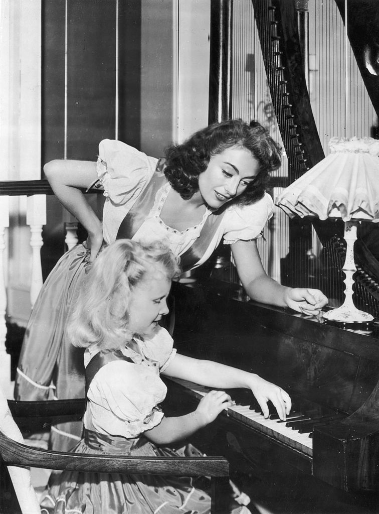 Joan Crawford y su hija Christina tocando el piano.| Fuente: Getty Images