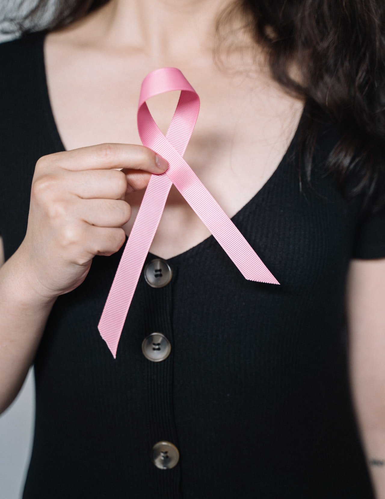 Mujer sostiene cinta rosa que simboliza la lucha contra en cáncer de seno. | Foto: Pexels