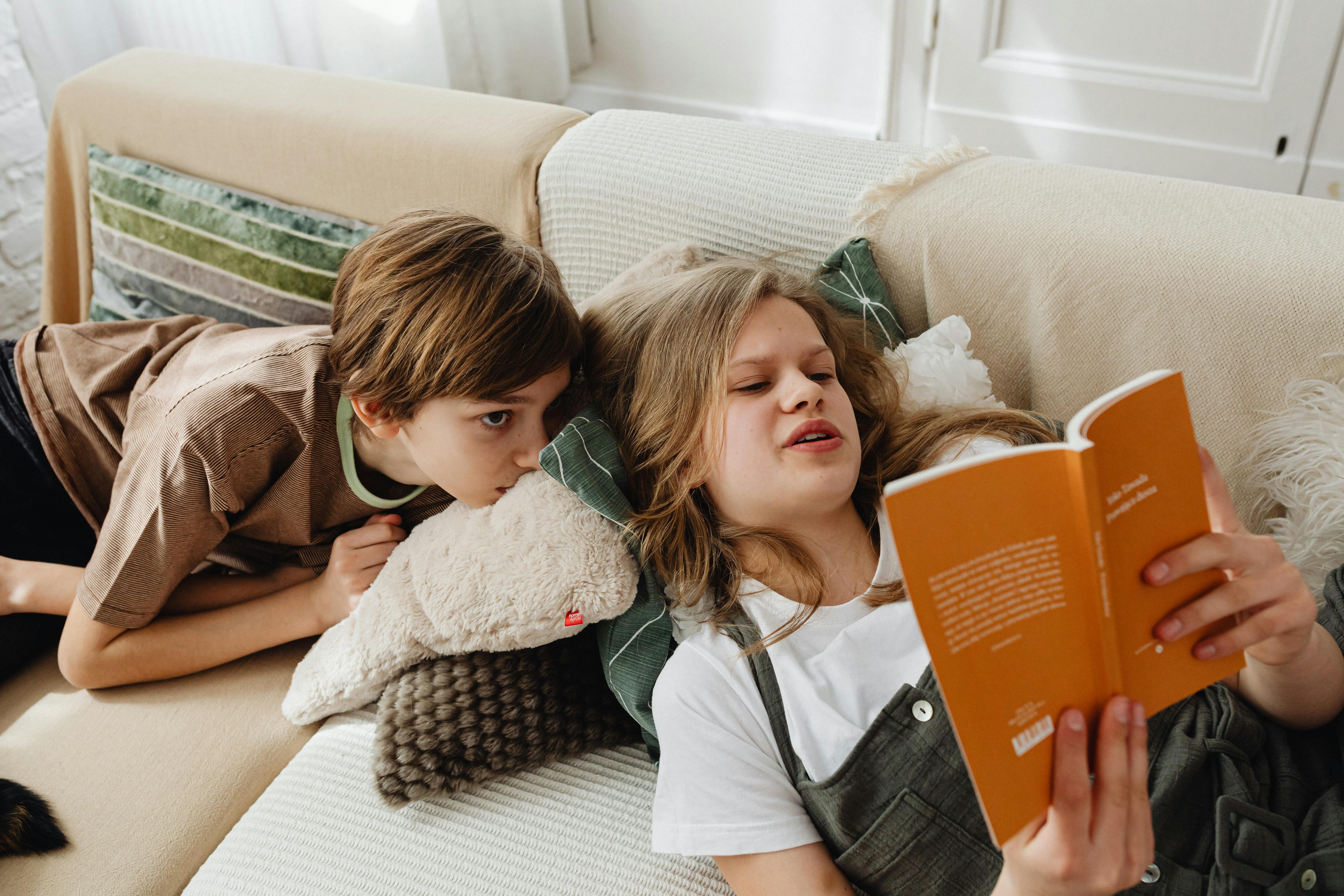 Una niña leyendo a su hermano | Fuente: Pexels