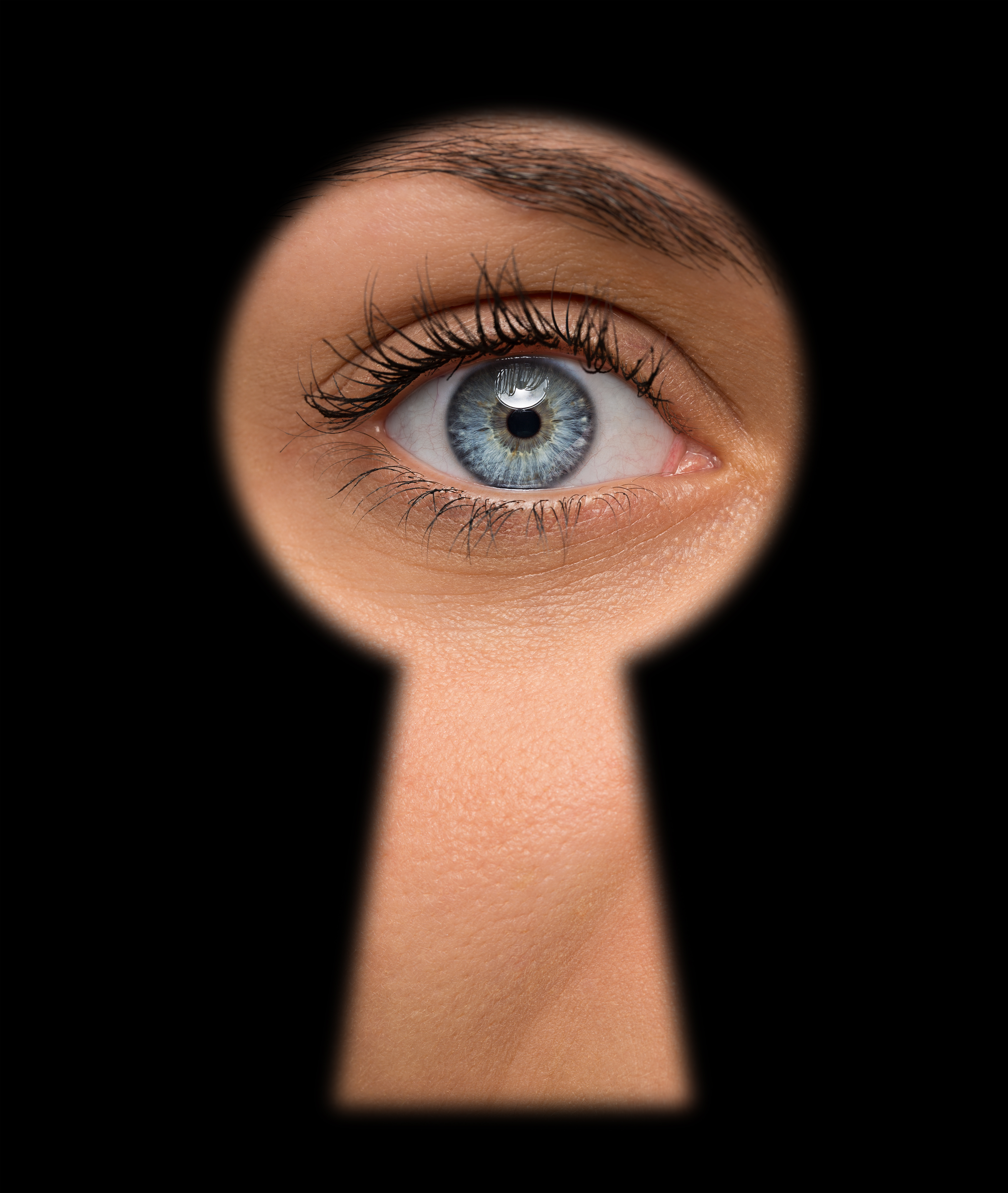 Mujer de ojos azules mirando por una cerradura | Foto: Shutterstock