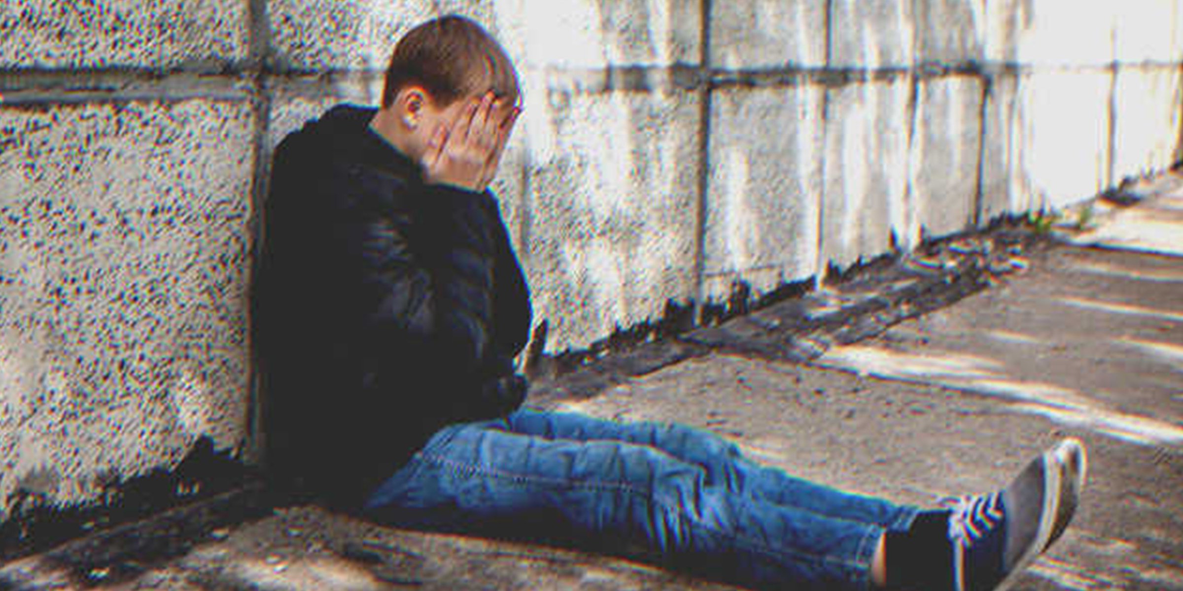 Joven llorando sentado en una acera. | Foto: Shutterstock