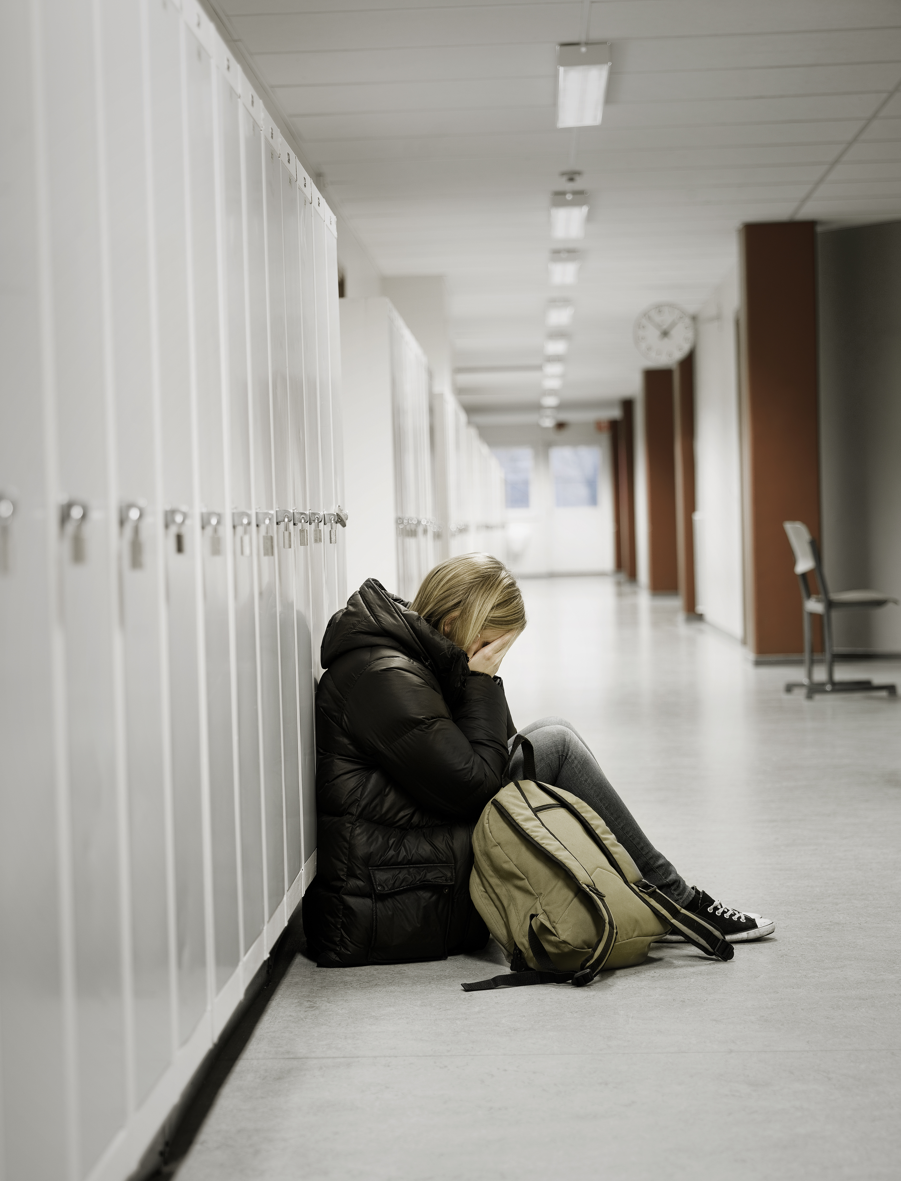 Joven llorando junto a las taquillas de la escuela. | Fuente: Shutterstock