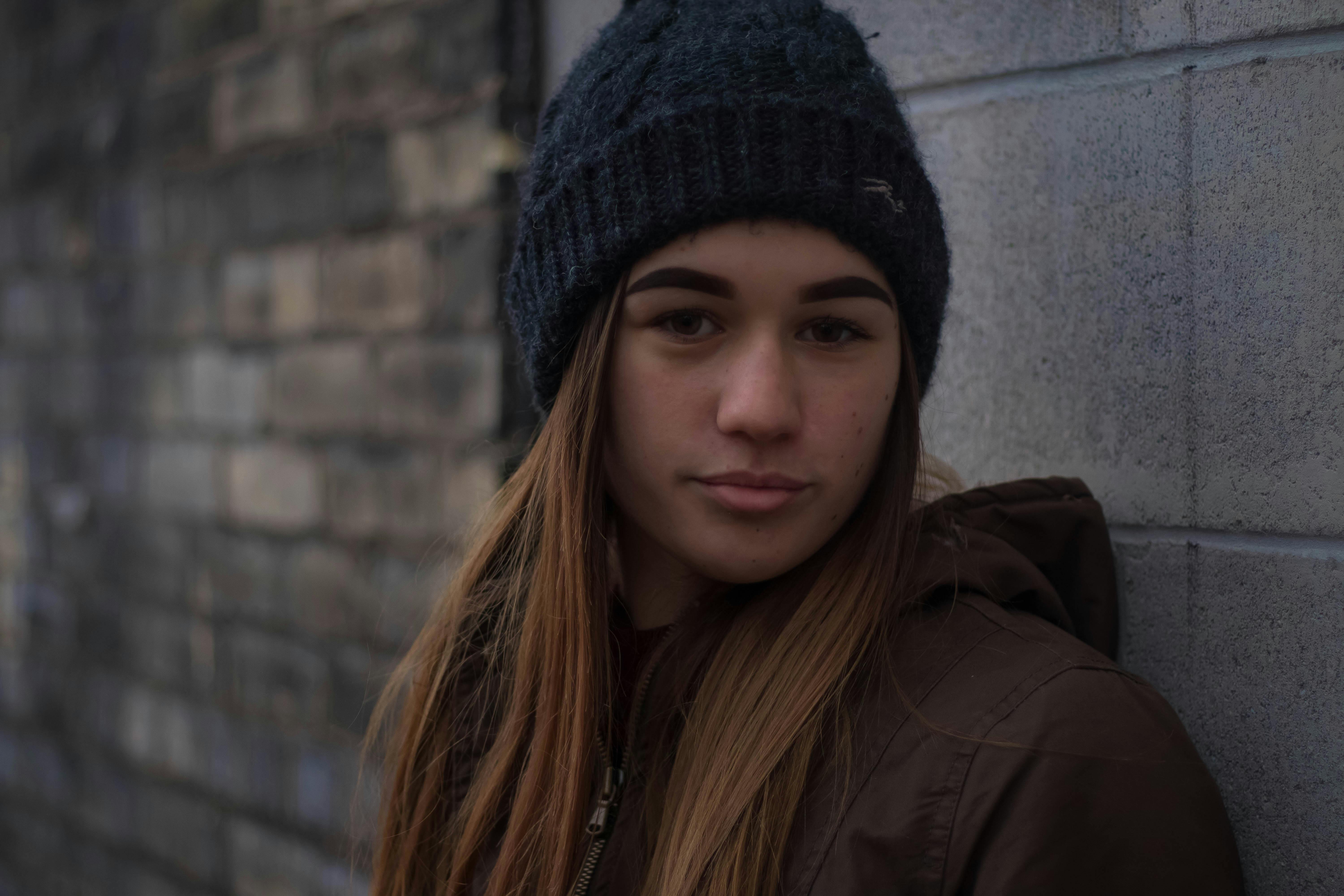 Una adolescente de aspecto neutro de pie contra una pared | Foto: Pexels