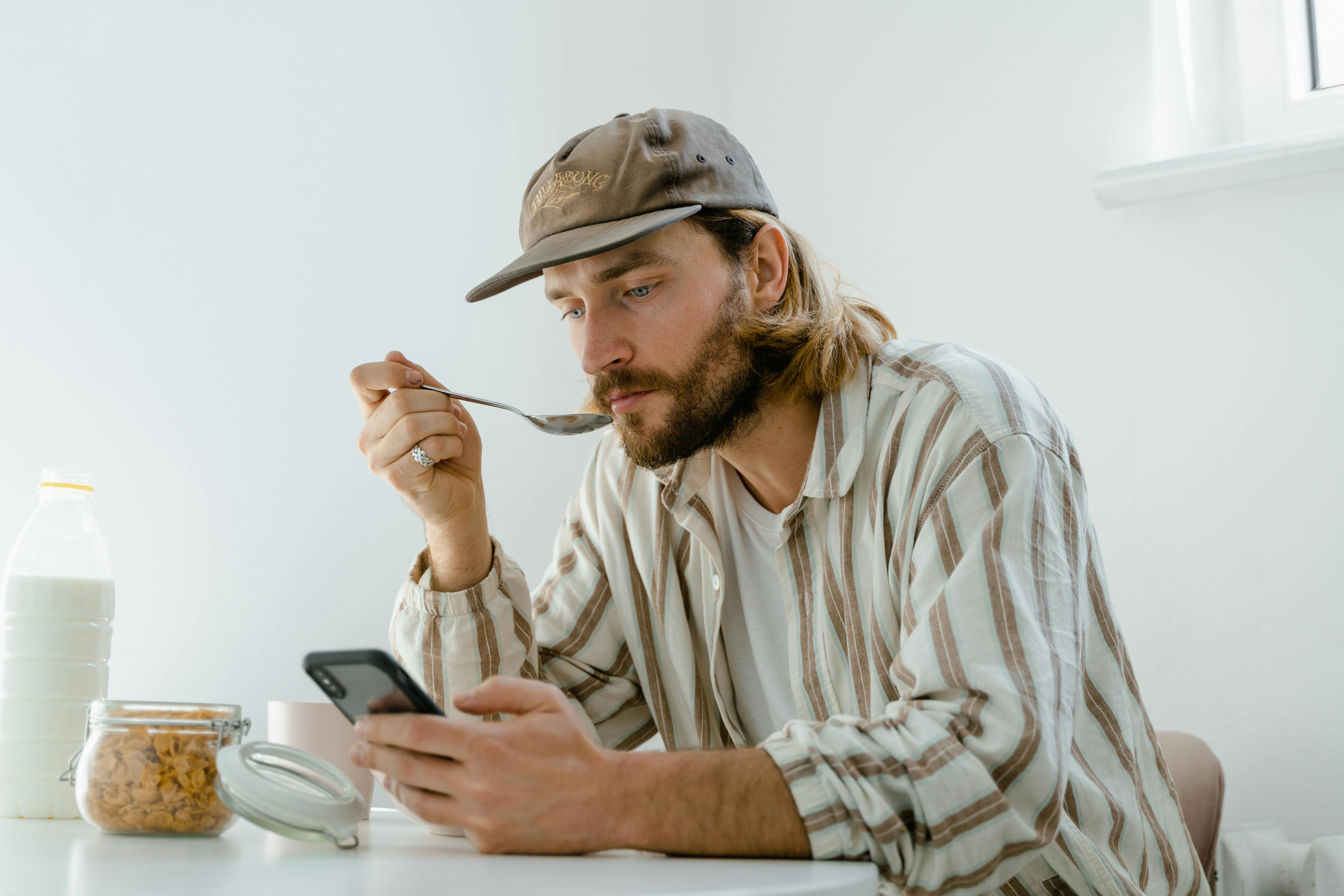 Un hombre enviando mensajes de texto mientras desayuna | Fuente: Pexels