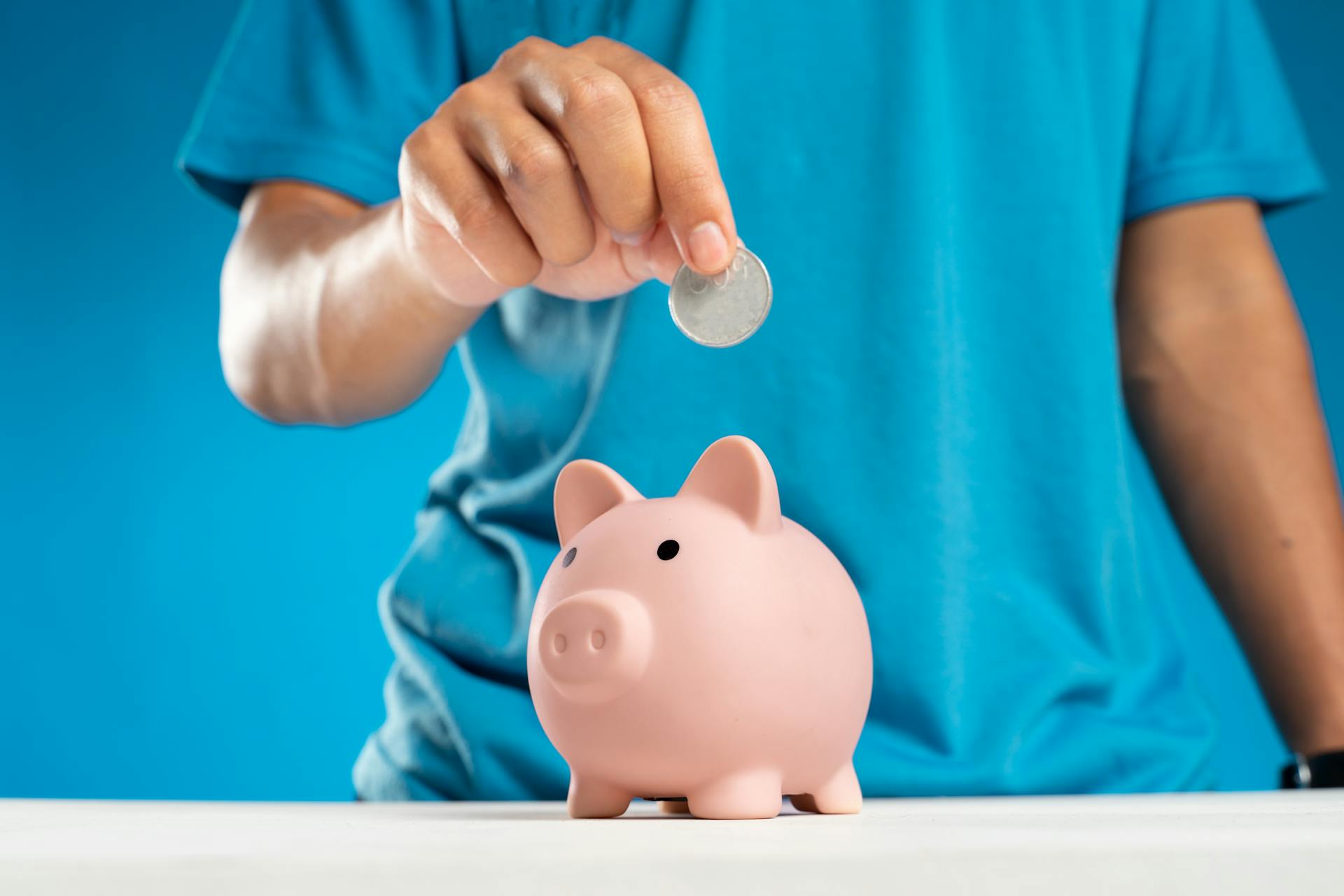 Persona metiendo una moneda en una alcancía | Fuente: Pexels