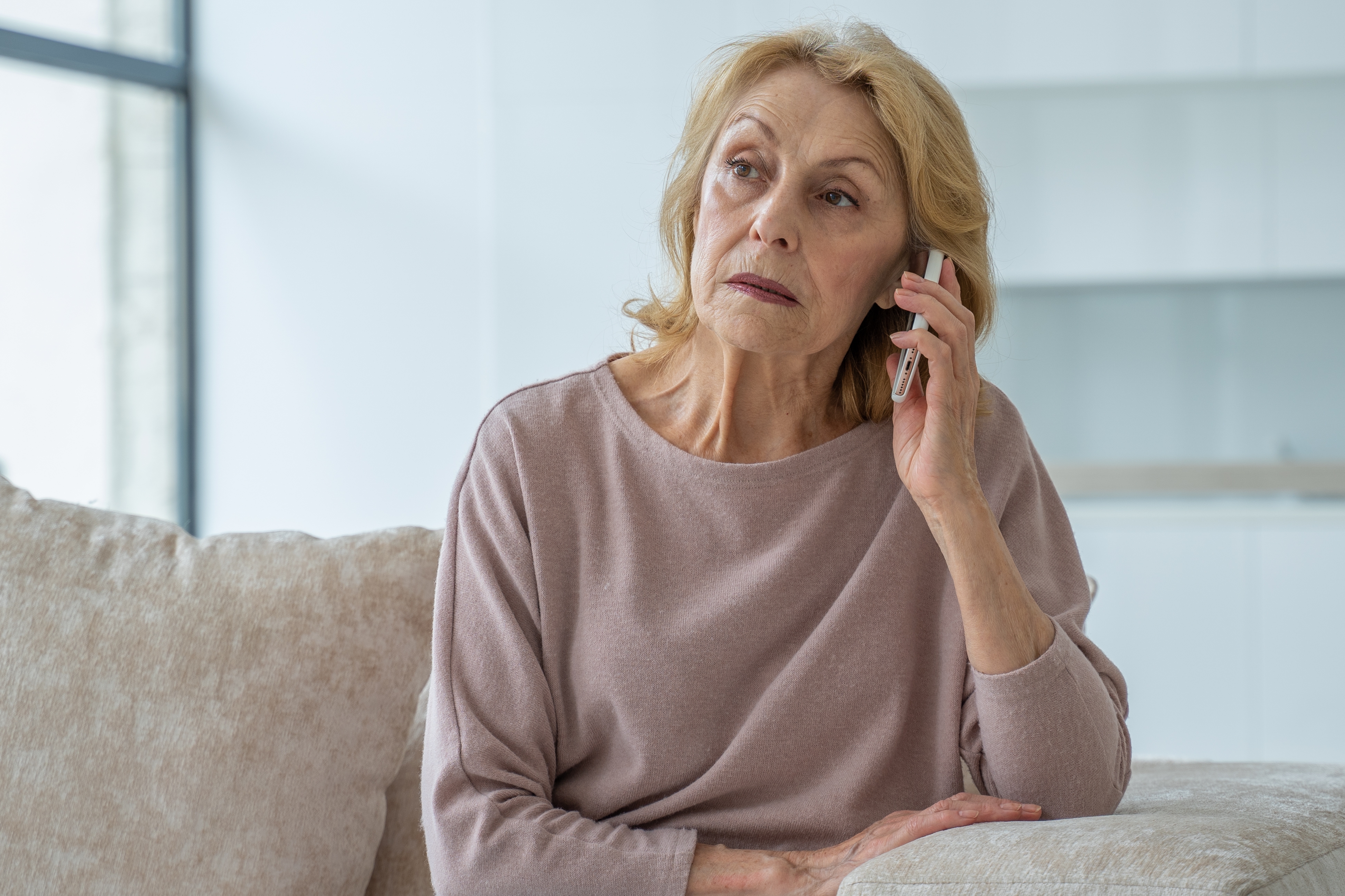 Una anciana con mirada triste mientras habla por teléfono | Fuente: Shutterstock