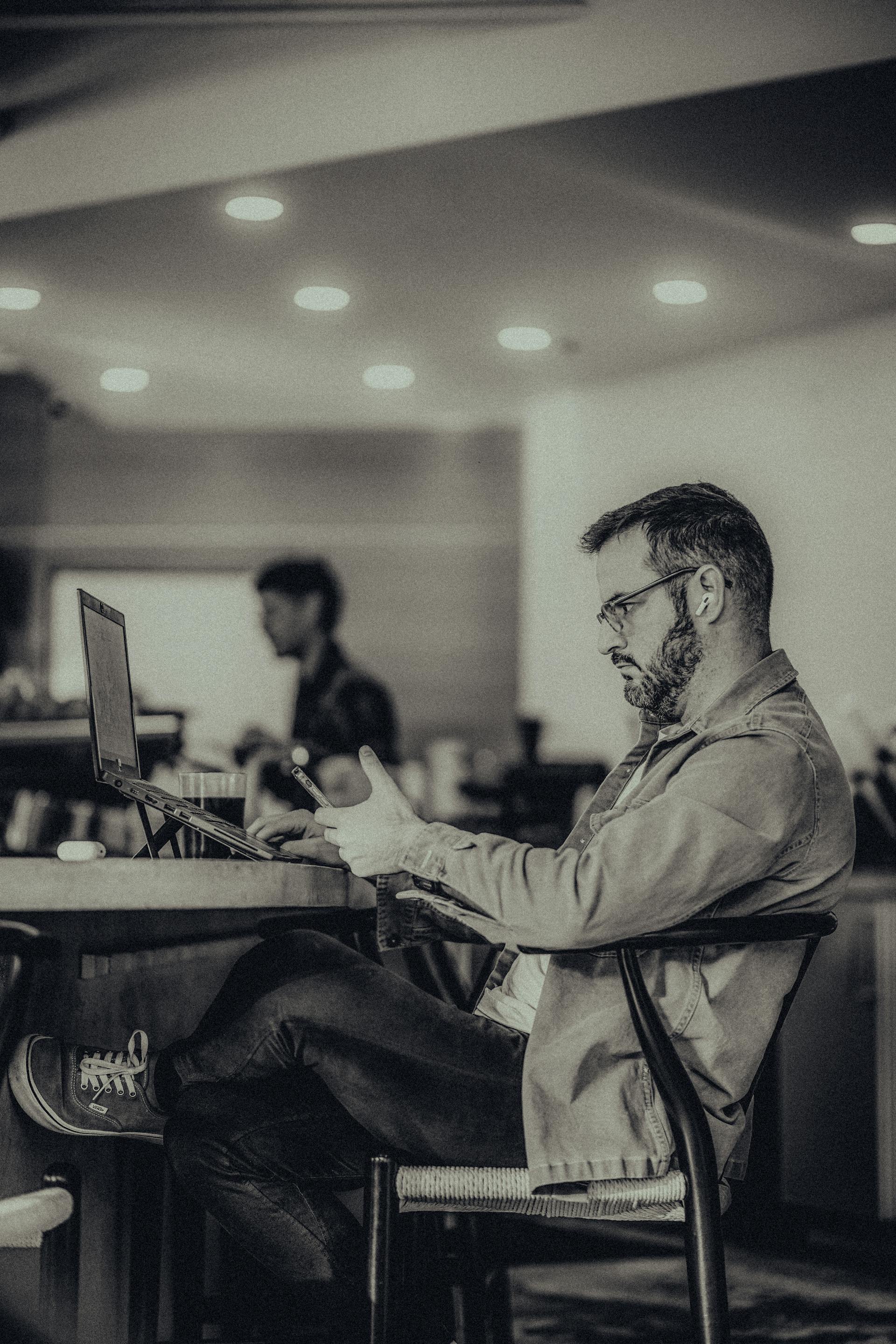 Un hombre sentado en una oficina y utilizando su teléfono | Fuente: Pexels