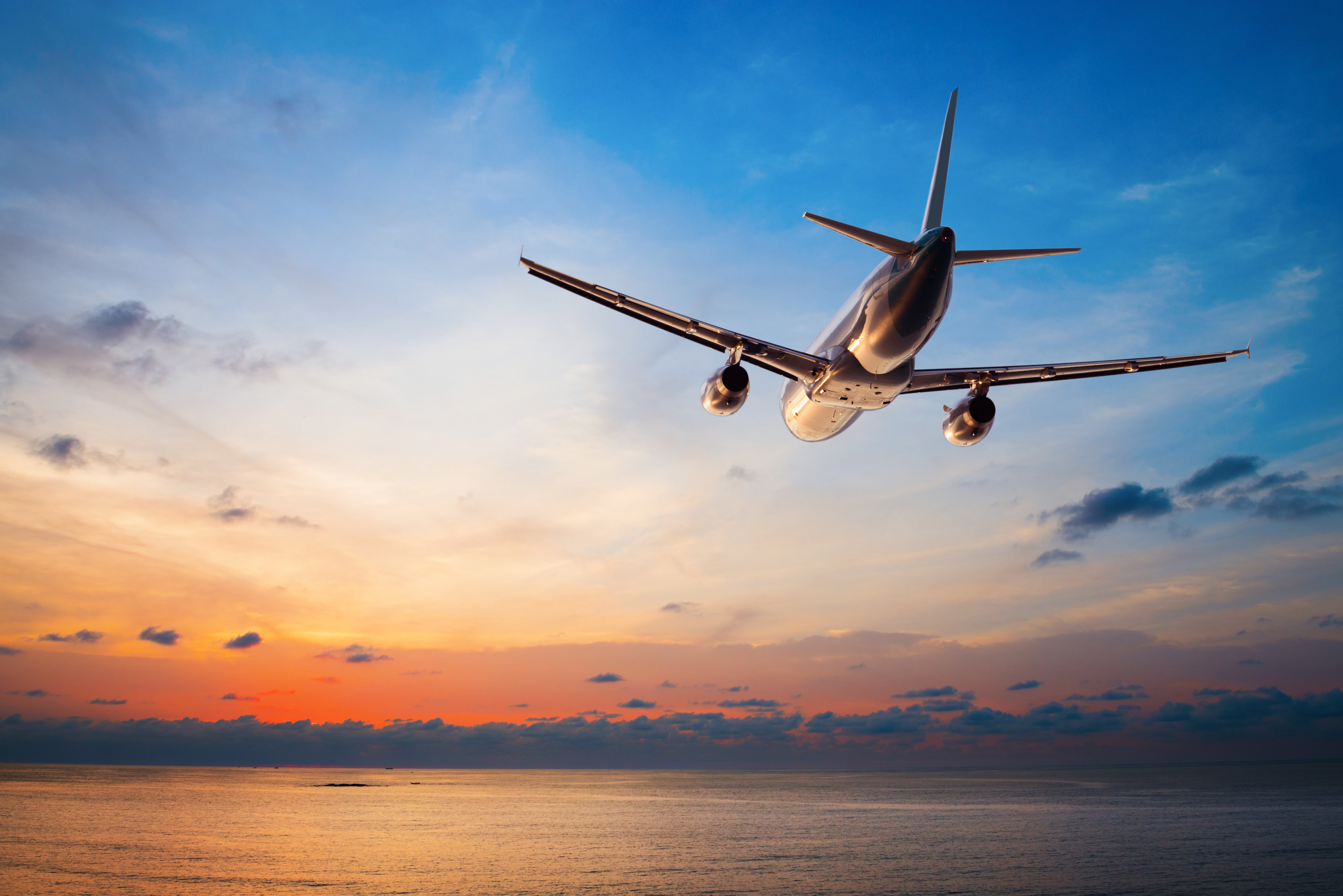 Un avión volando sobre un fondo de puesta de sol | Fuente: Shutterstock