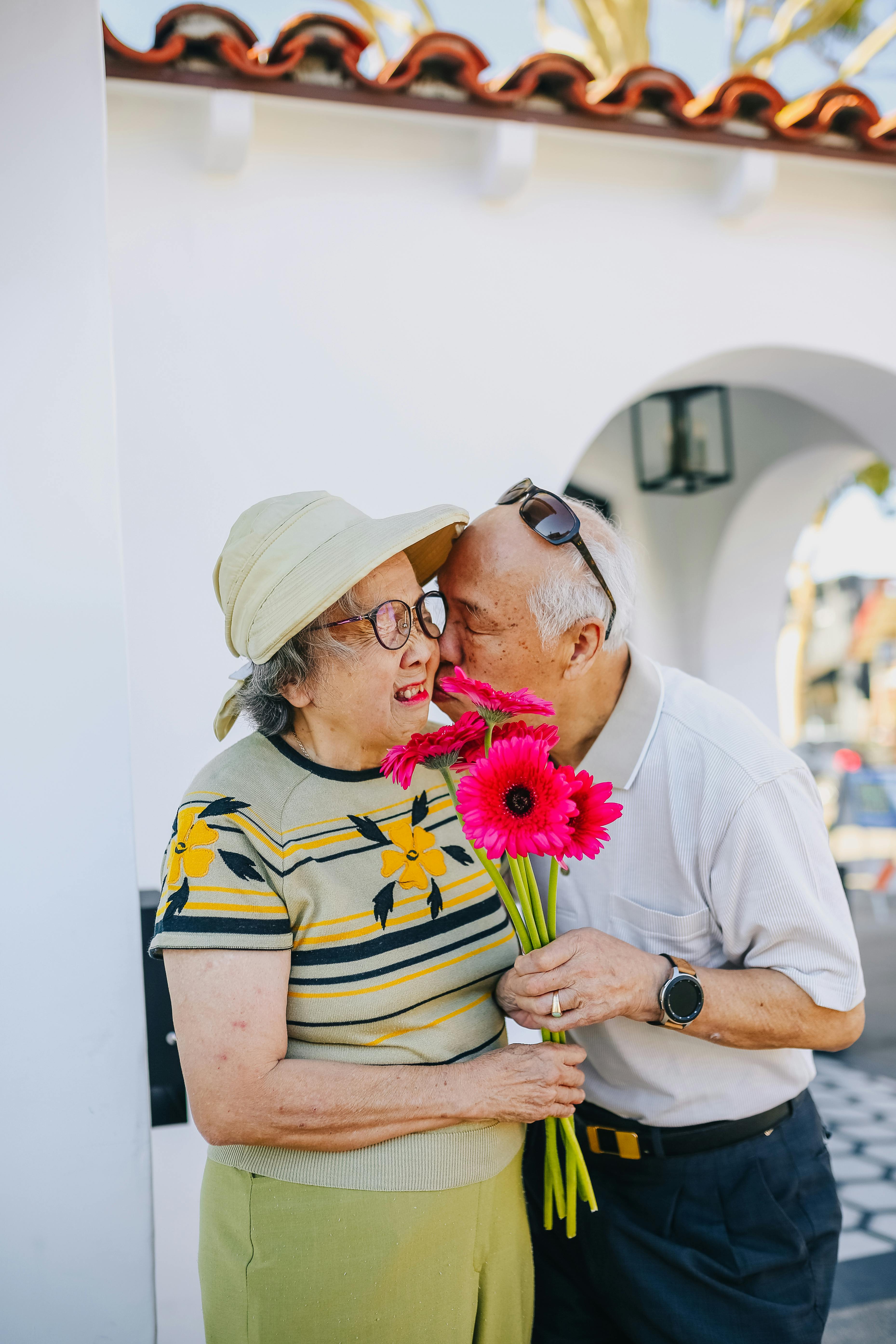 Una pareja en actitud romántica mientras la mujer recibe un ramo de flores | Foto: Pexels