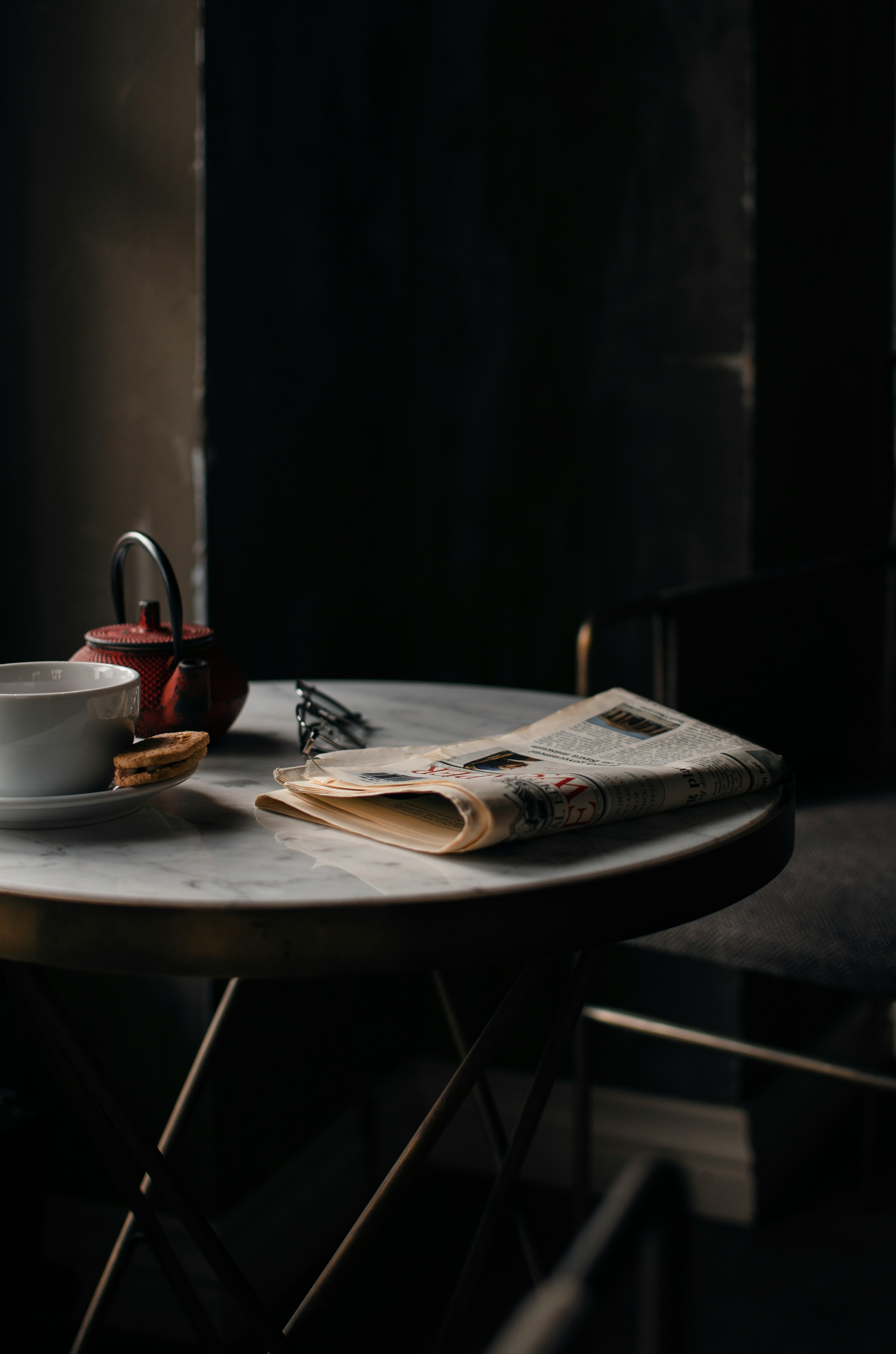 Un bollitore e una tazza di caffè accanto a un giornale ben piegato | Fonte: Unsplash