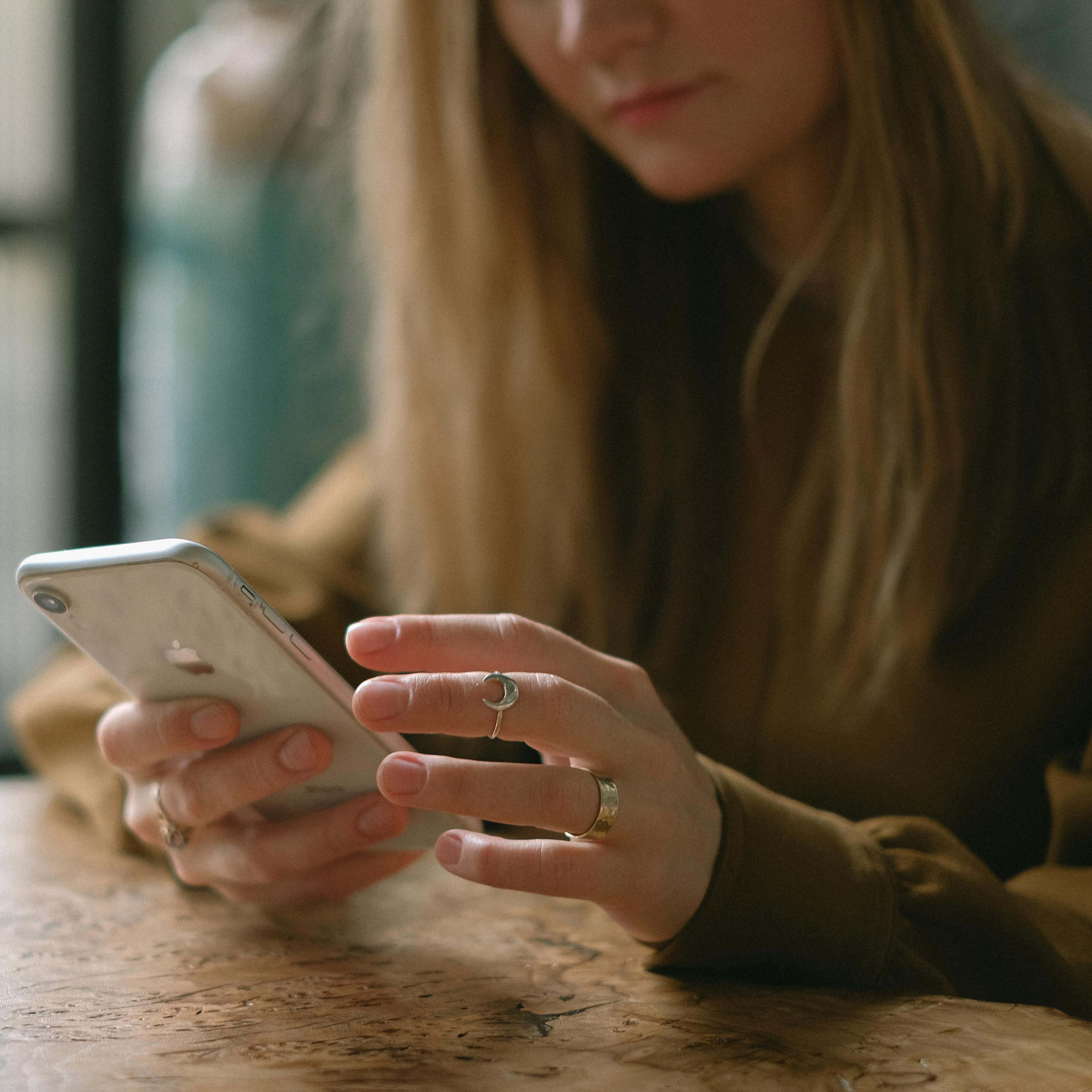 Una mujer sentada en la mesa de un restaurante, mirando su teléfono | Fuente: Pexels