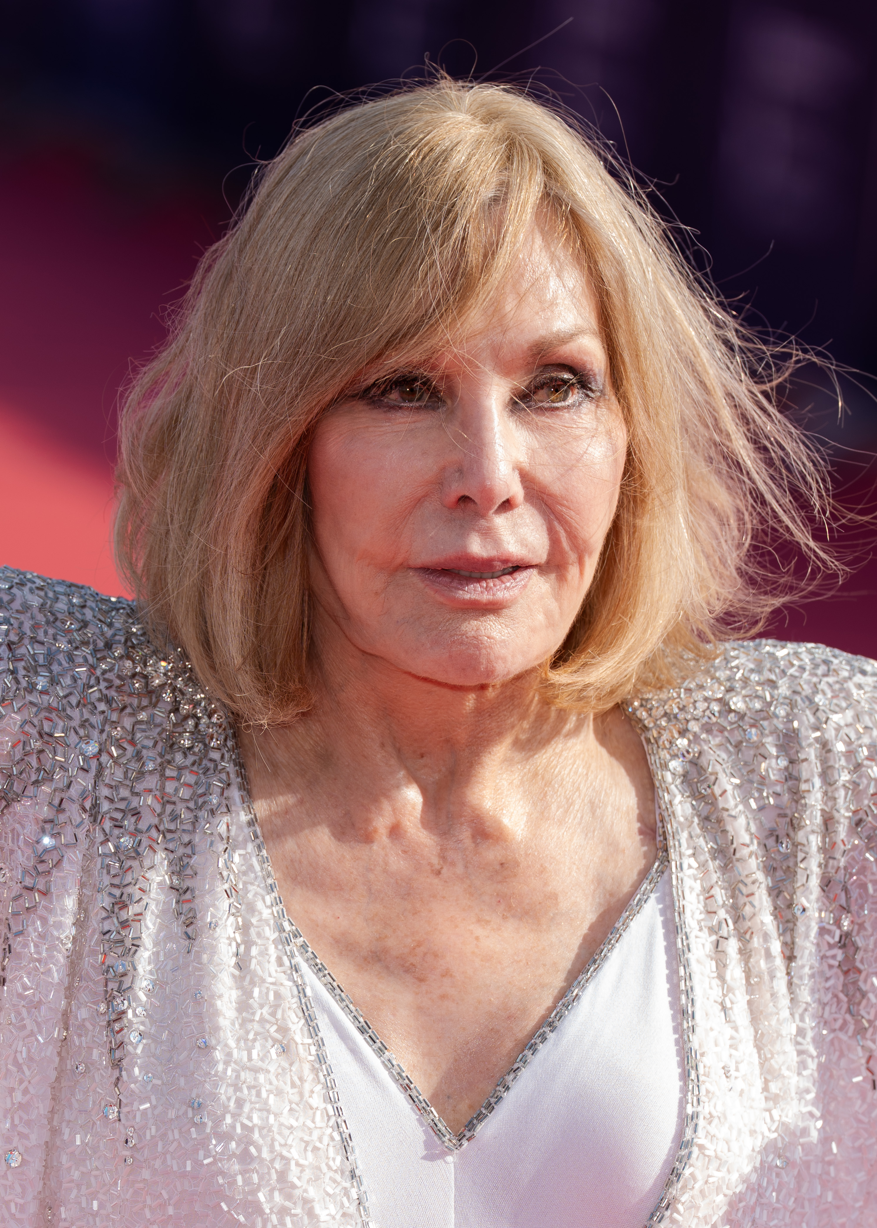 Kim Novak llega al 51.º Festival de Cine Americano de Deauville el 6 de septiembre de 2025, con un chal transparente en blanco y negro sobre un conjunto oscuro. Camina junto a otra mujer a la salida del recinto, a la luz del día. | Fuente: Getty Images