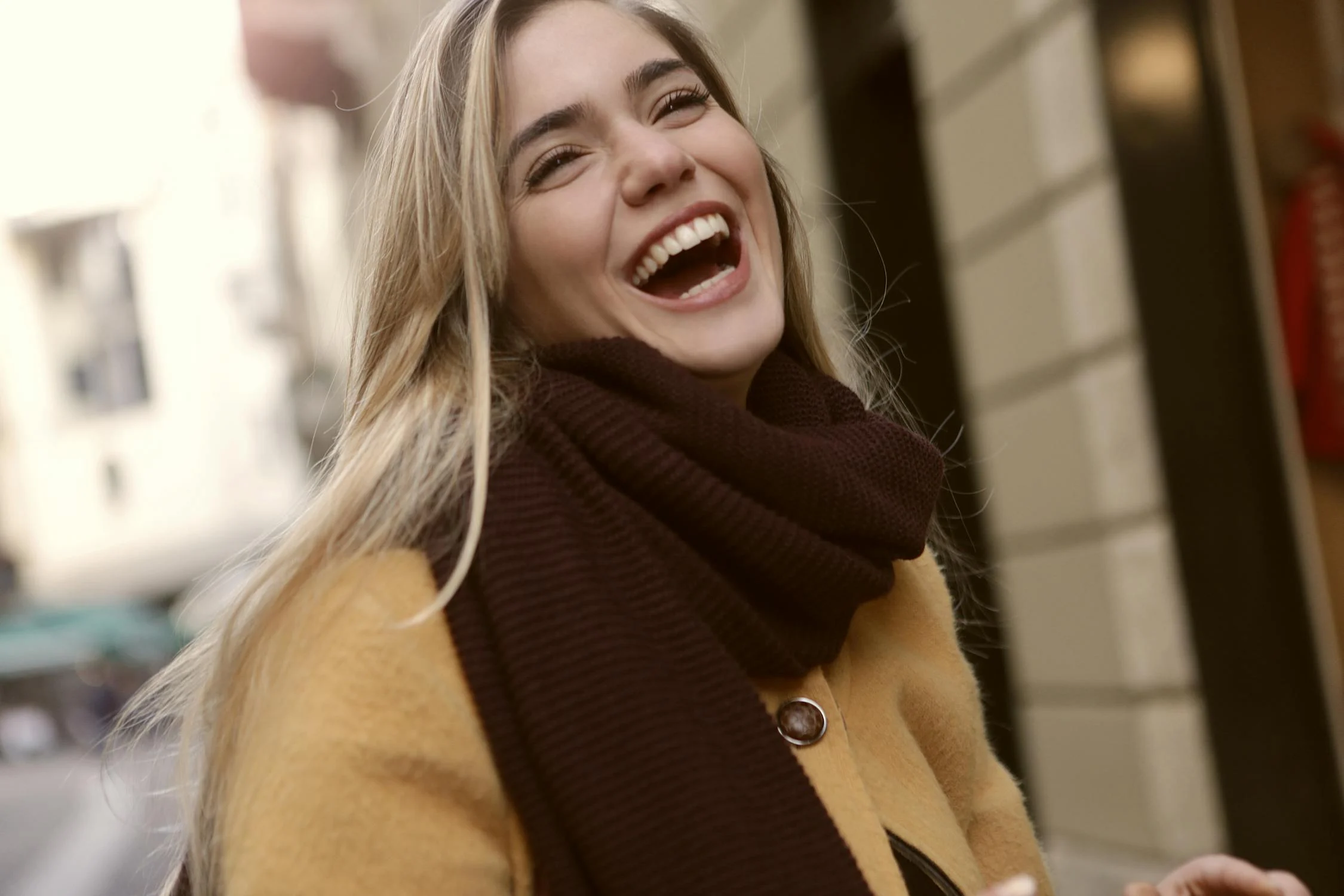 Una mujer rubia riendo al aire libre ⏐ Fuente: Pexels