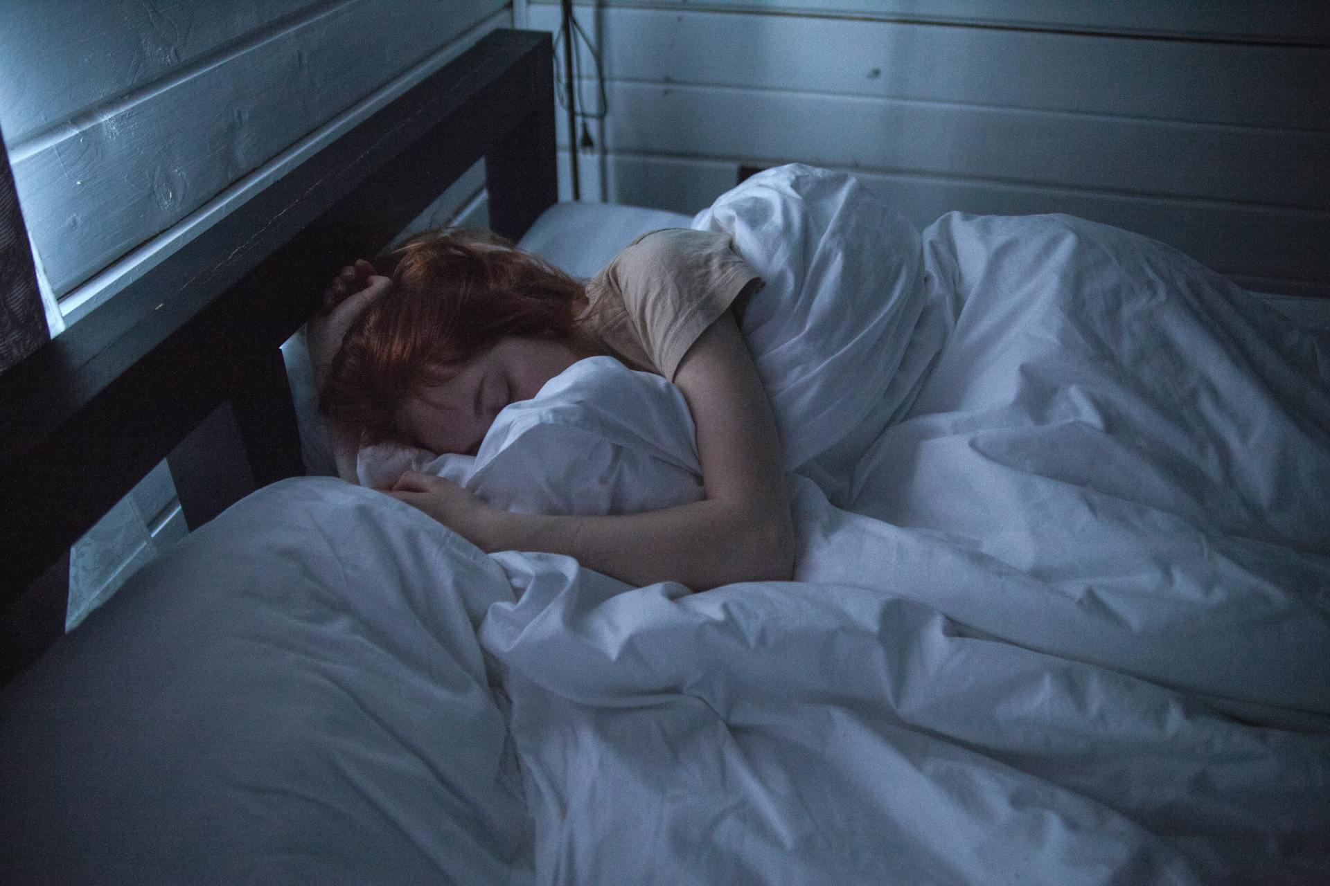 Mujer envuelta en sábanas en la cama | Foto: Pexels